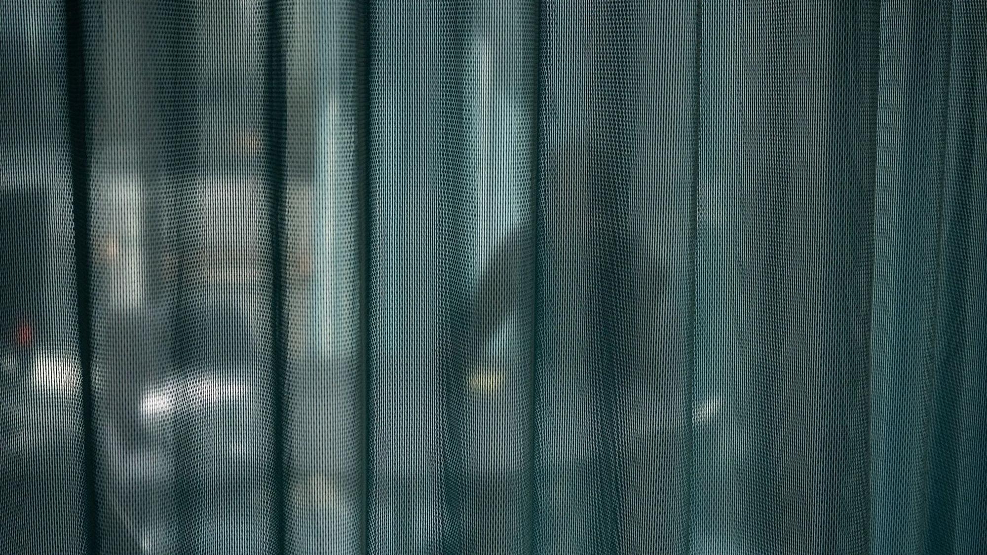 Ein Mann sitzt in einem Büro hinter einem Vorhang
