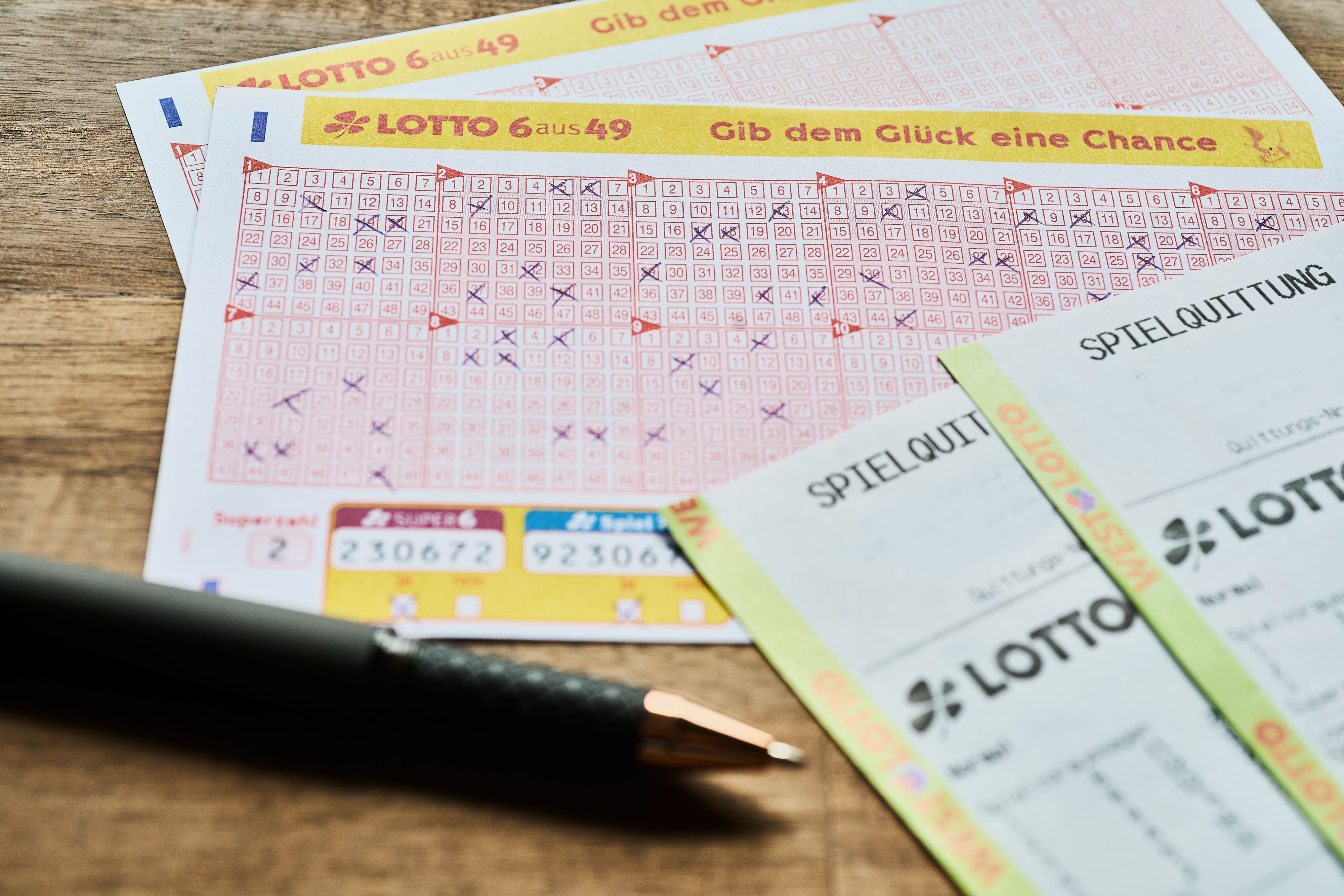 Auf einem Tisch liegt ein LOTTO 6aus49 Tippschein sowie die Spielquittung.