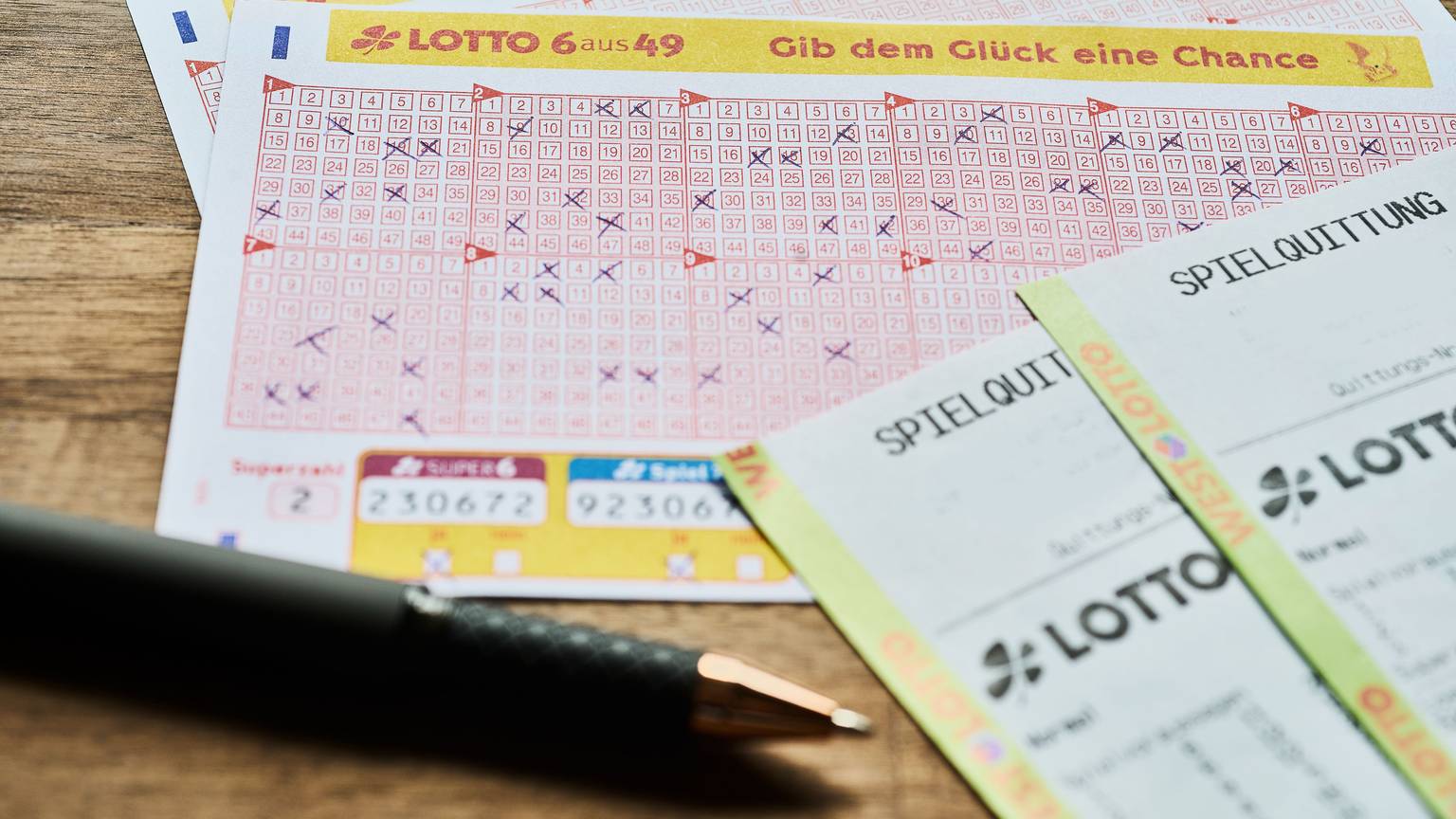Auf einem Tisch liegt ein LOTTO 6aus49 Tippschein sowie die Spielquittung.