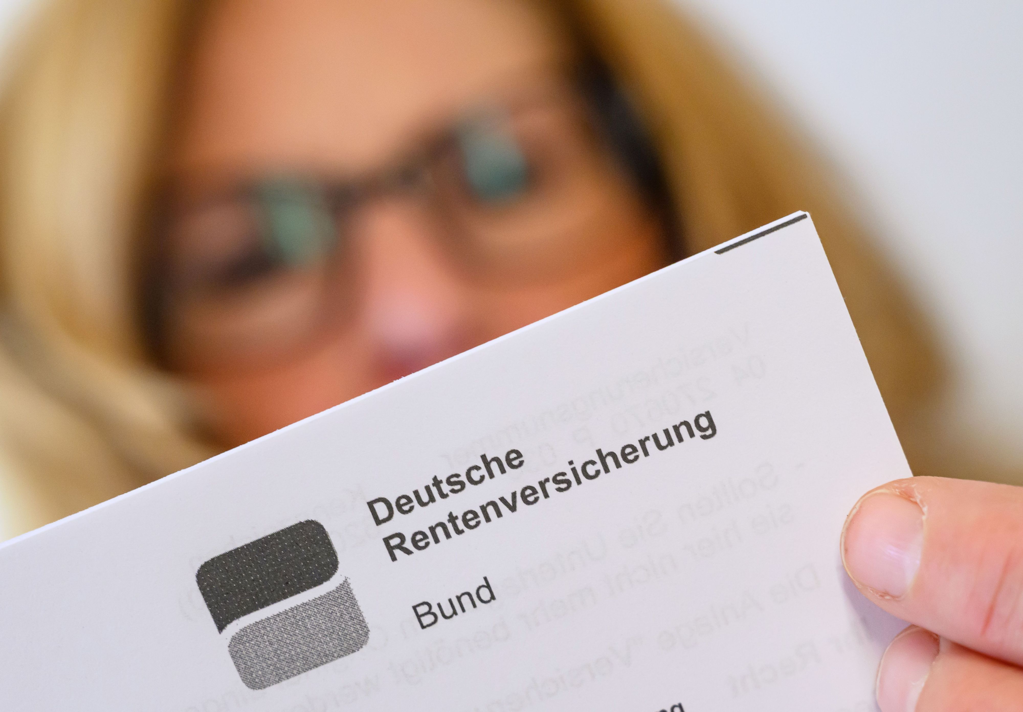 Eine Frau liest ein Schreiben der Deutschen Rentenversicherung in ihrer Wohnung. (Symbolbild)