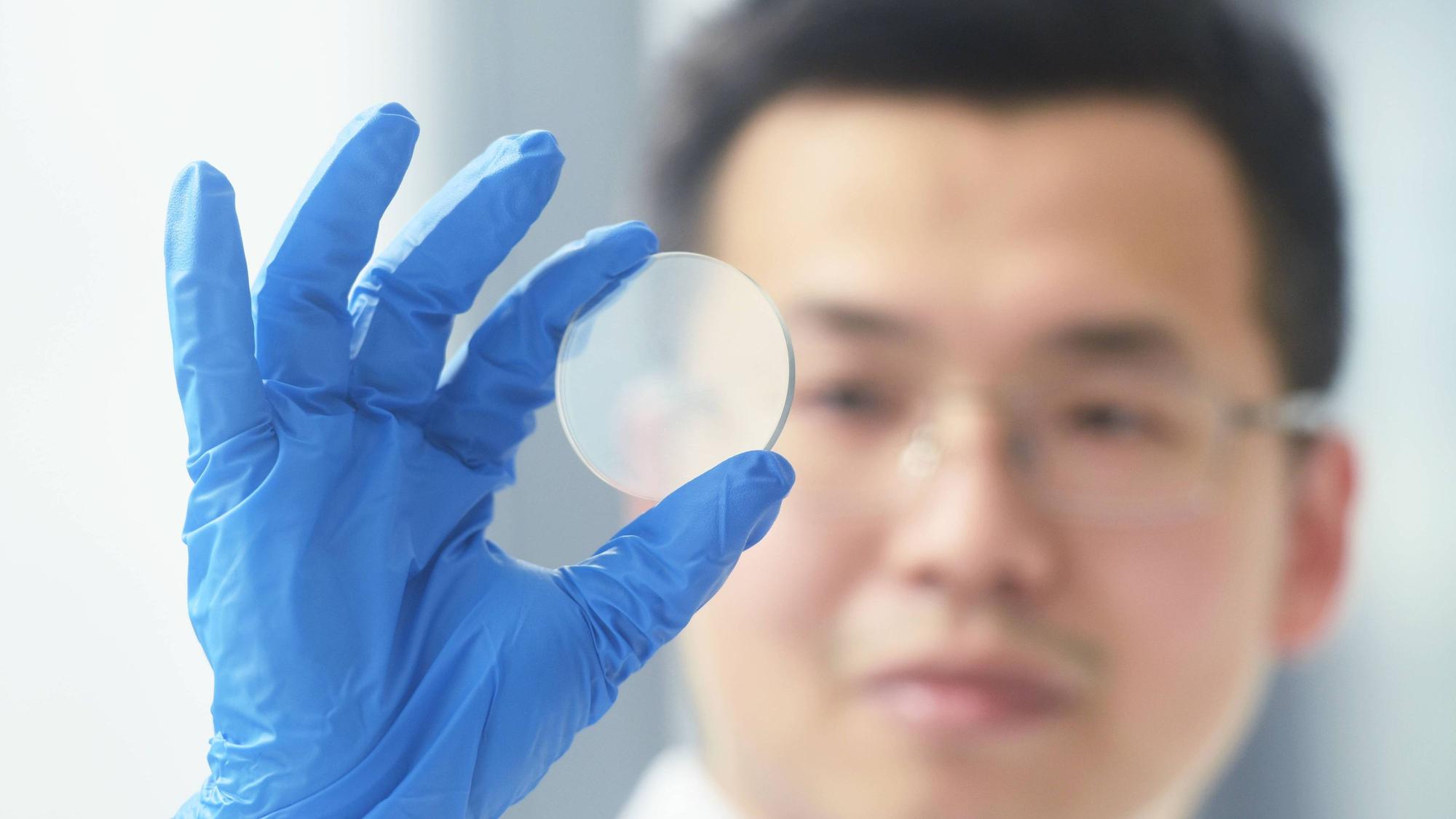 Ein Forscher der Universität Hangzhou begutachtet einen Gallium-Oxid-Wafer. Auf Basis dieses Trägers können Mikrochips hergestellt werden.