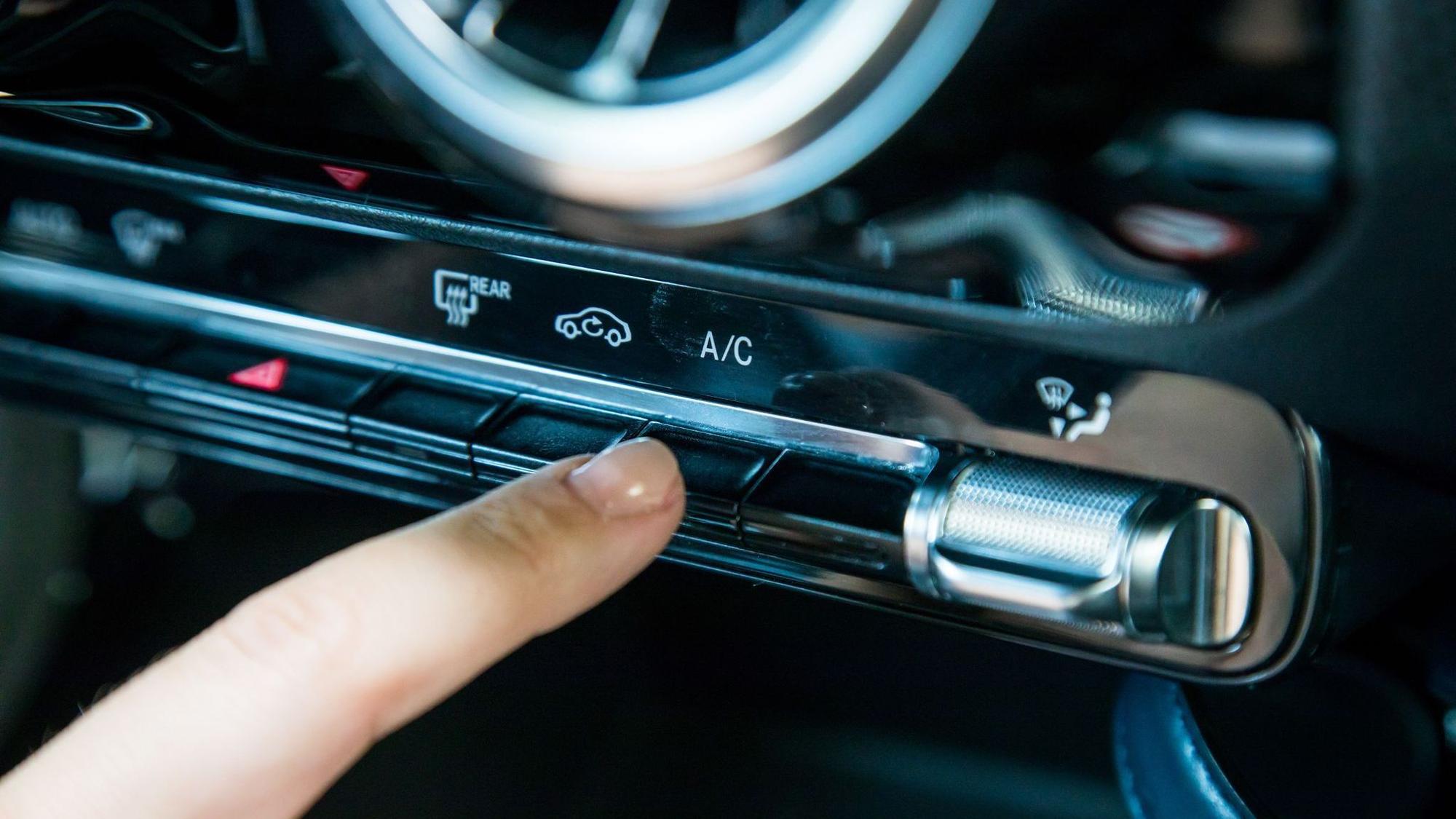 Eine Frau aktiviert die Klimaanlage in einem Auto