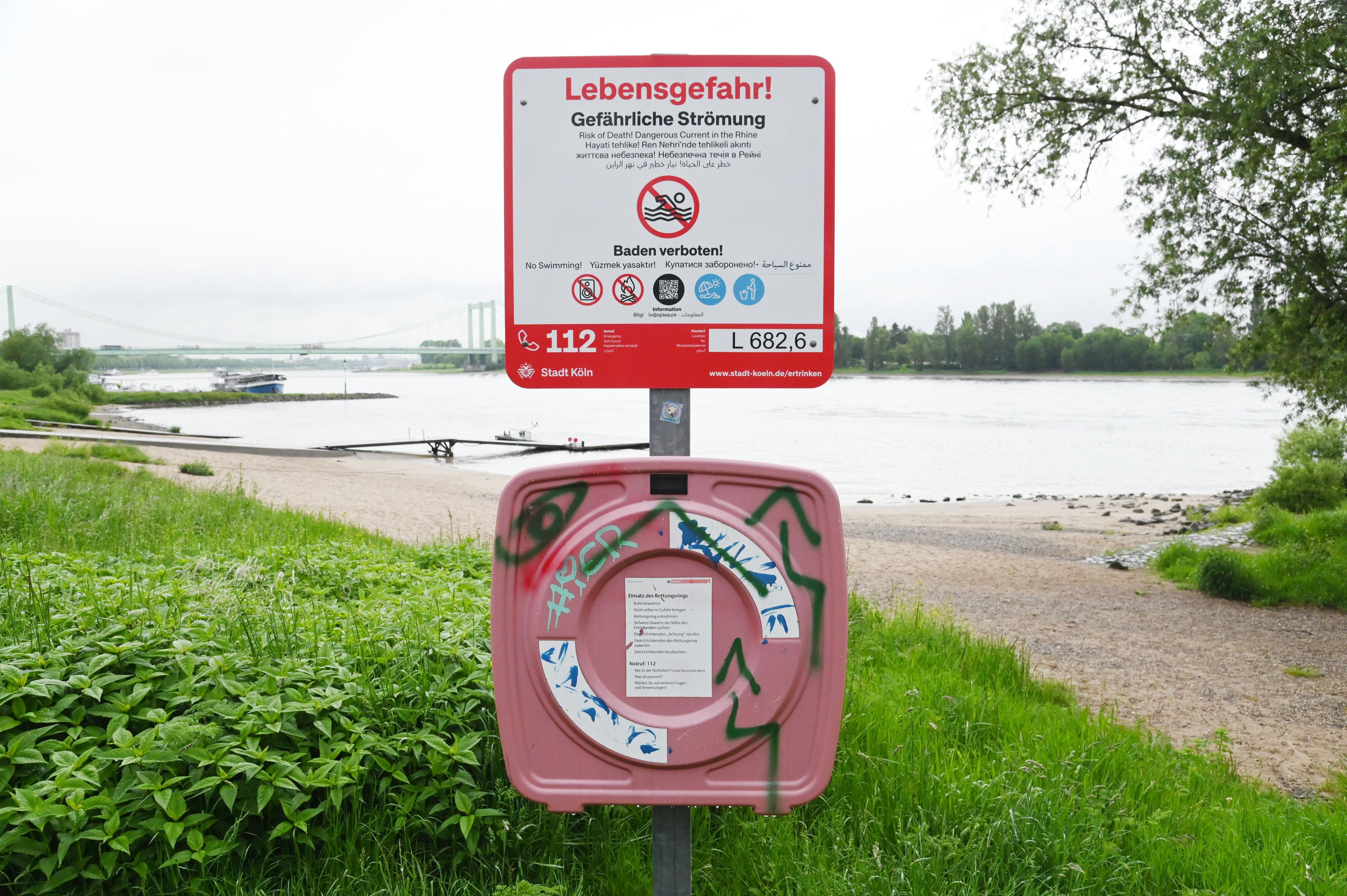 Am Rheinufer stehen neue Schilder, die auf das Badeverbot im Rhein hinweisen.