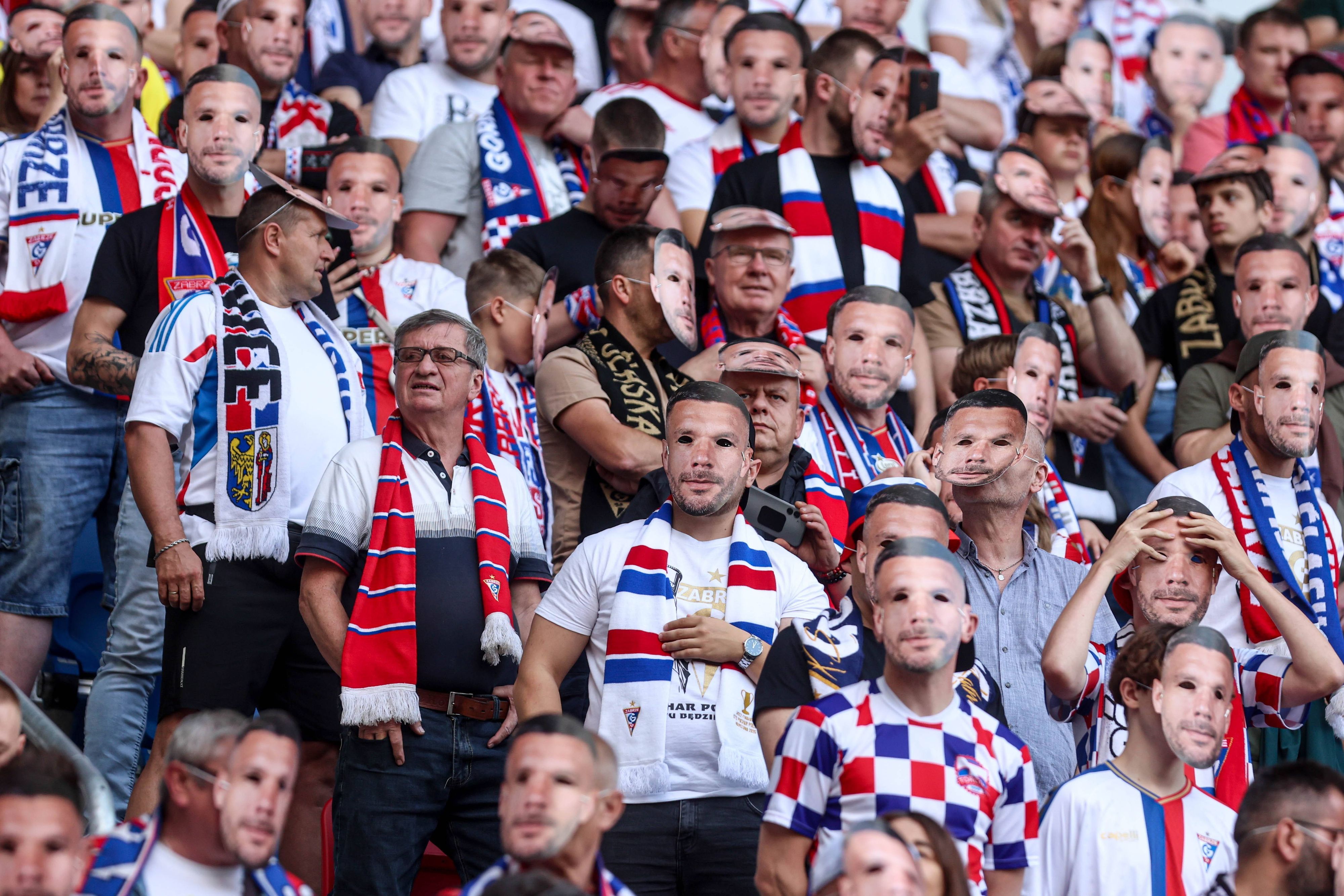 Fans mit der Maske von Lukas Podolski im Stadion.