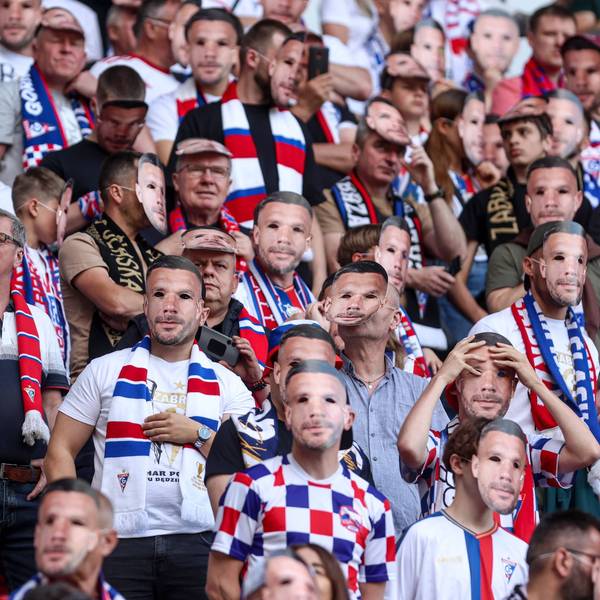 Fans mit der Maske von Lukas Podolski im Stadion.