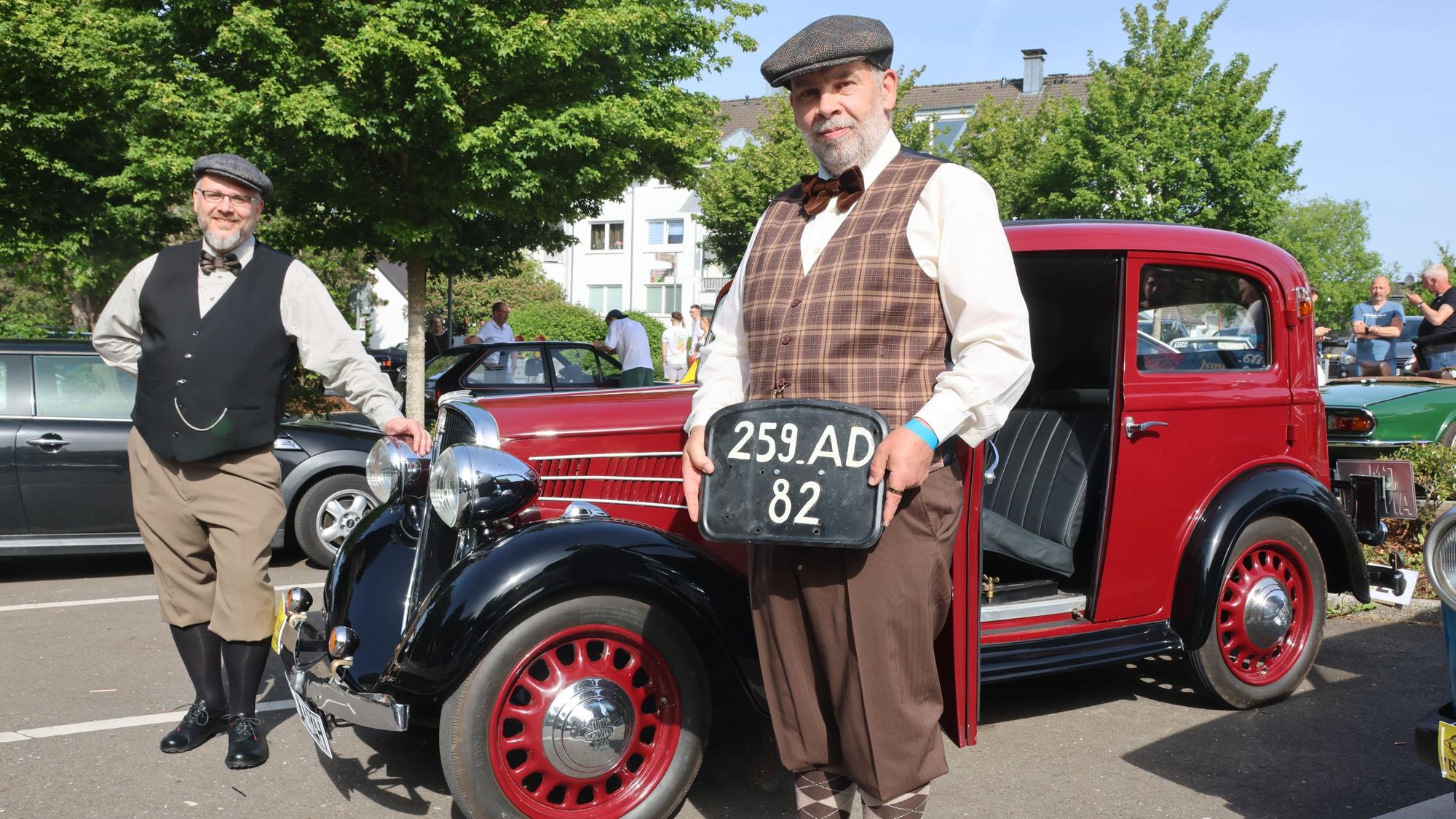Das Foto zeigt zwei Teilnehmer in stilechter Kleidung mit dem ältesten Fahrzeug (1934) im Teilnehmerfeld und dem Originalkennzeichen.
