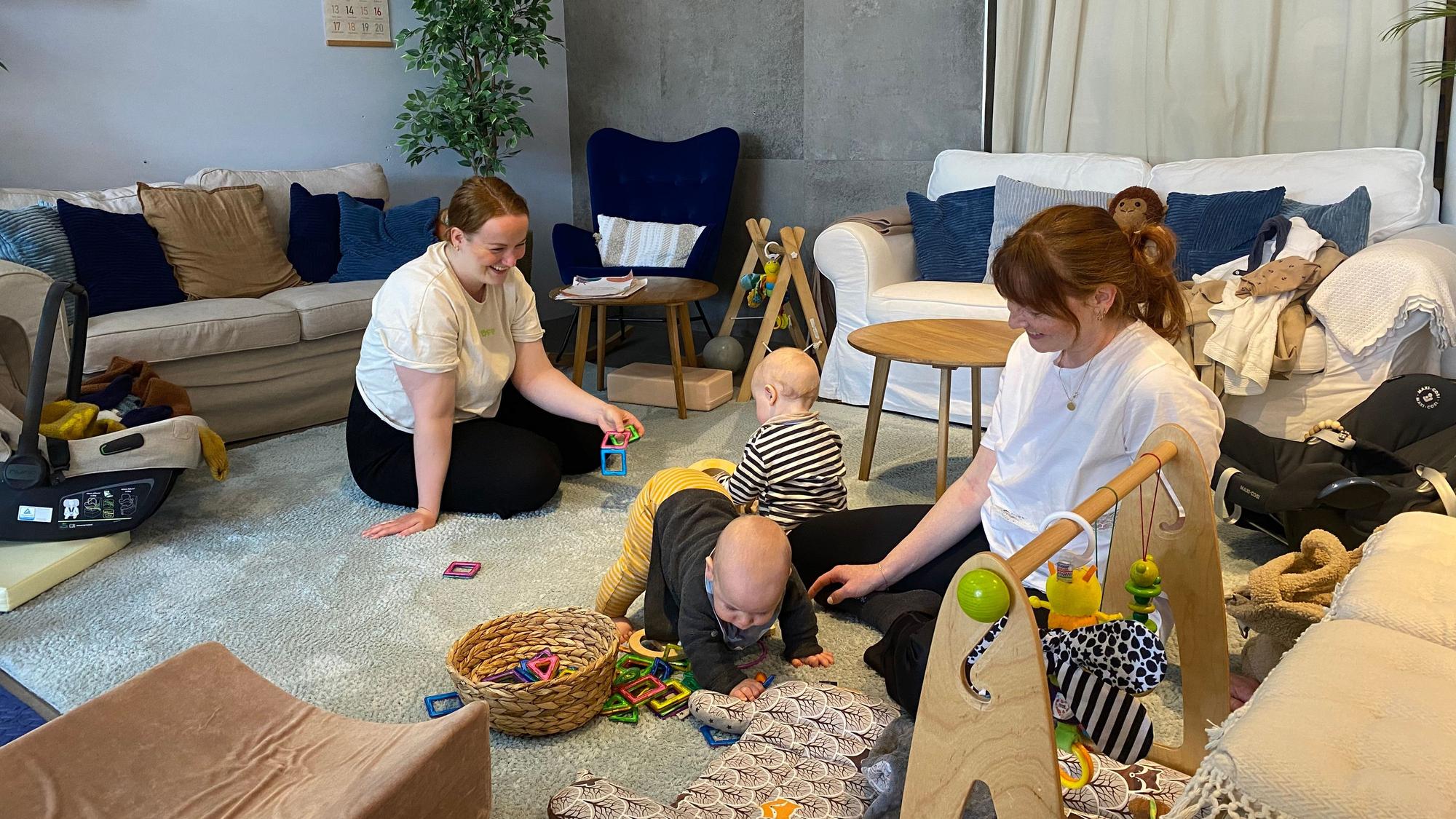 Zwei Frauen sitzen auf dem Boden mit ihren Babys.
