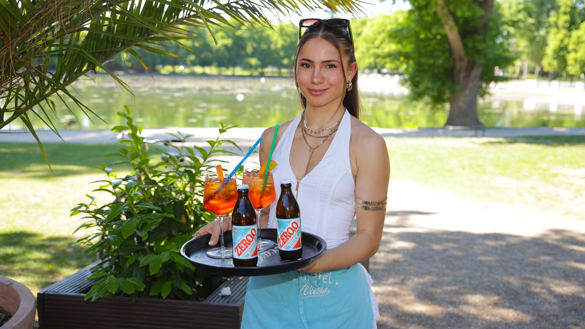 Service-Mitarbeiterin Alisah serviert Getränke im Biergarten am Aachener Weiher.