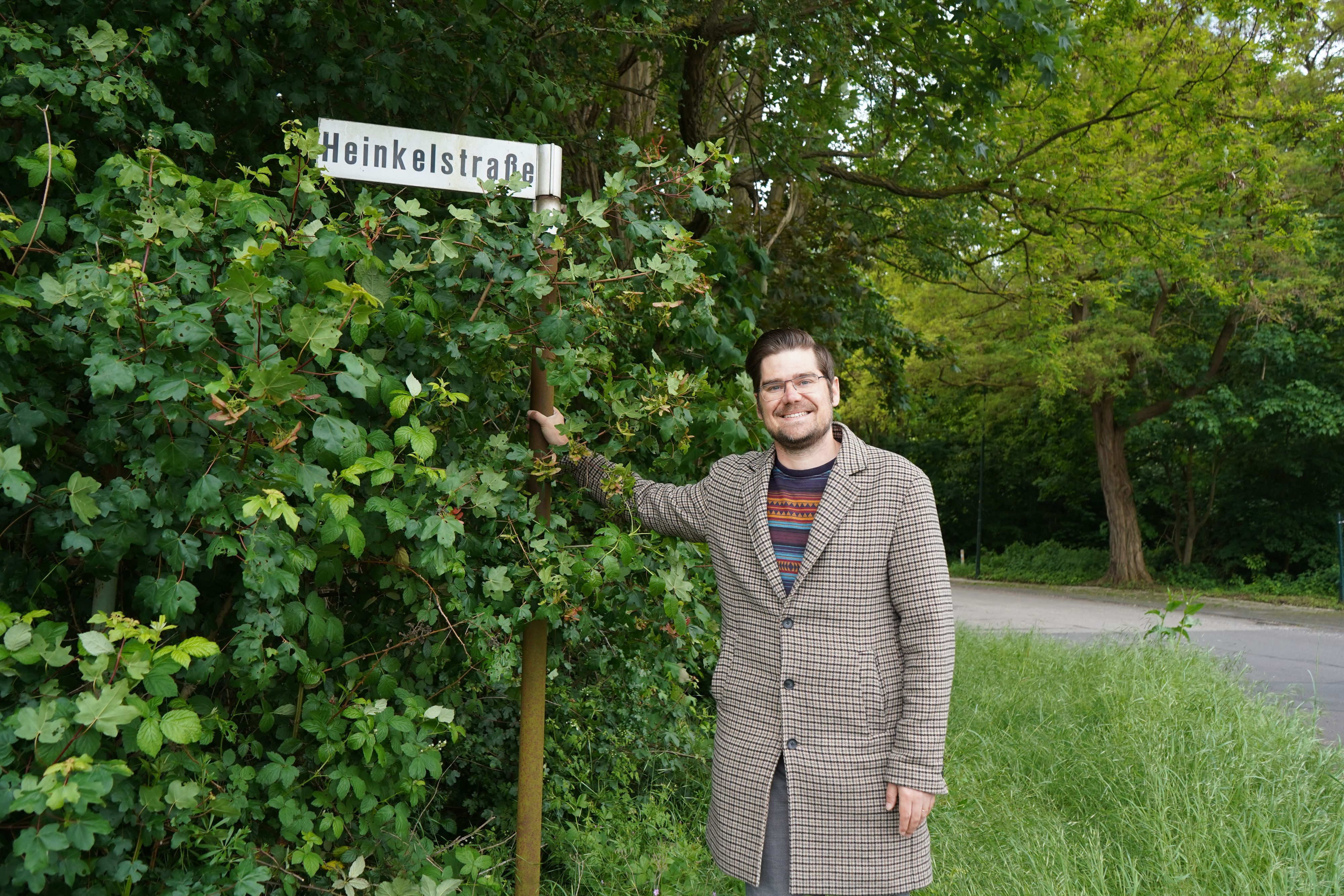 Das Foto zeigt einen Mann vor einem Straßenschild.