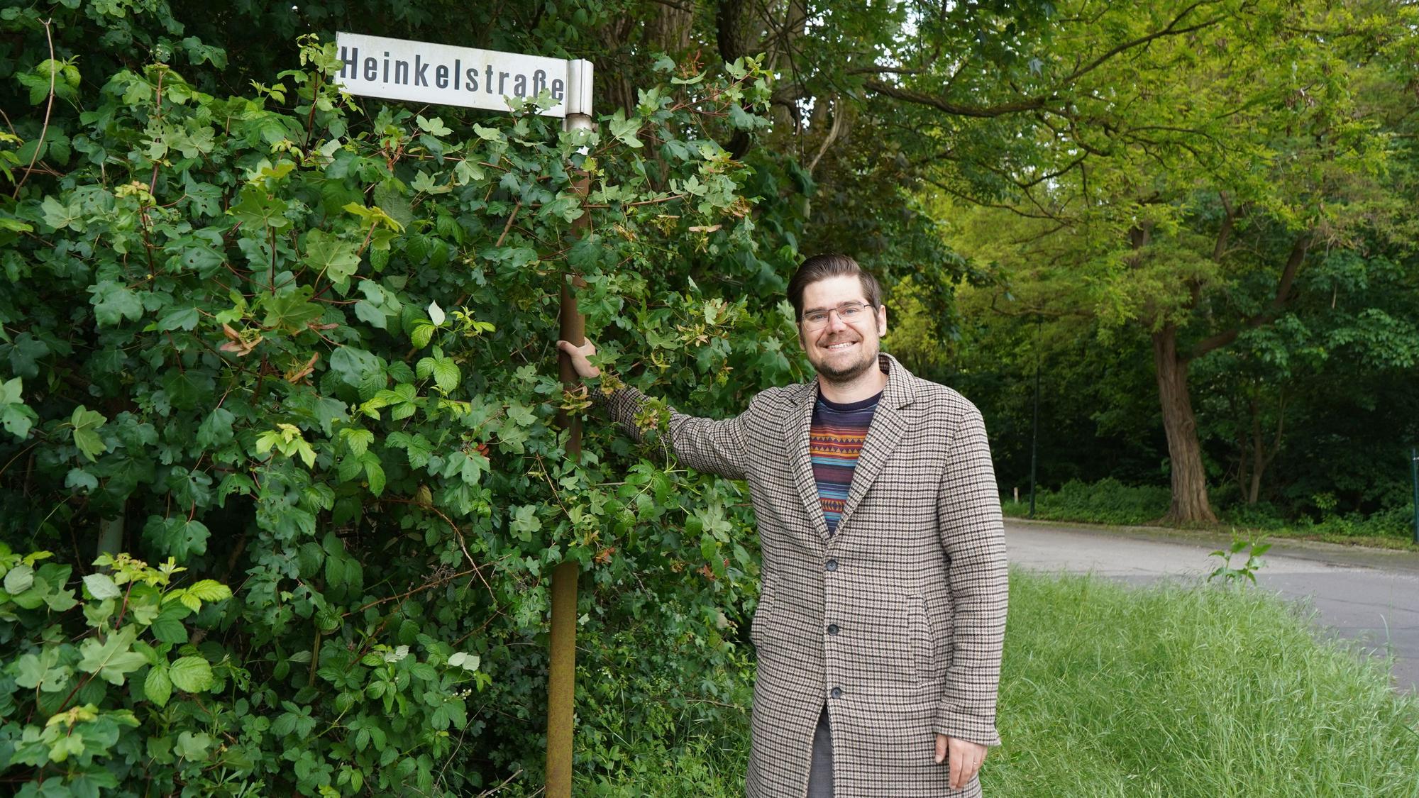 Das Foto zeigt einen Mann vor einem Straßenschild.