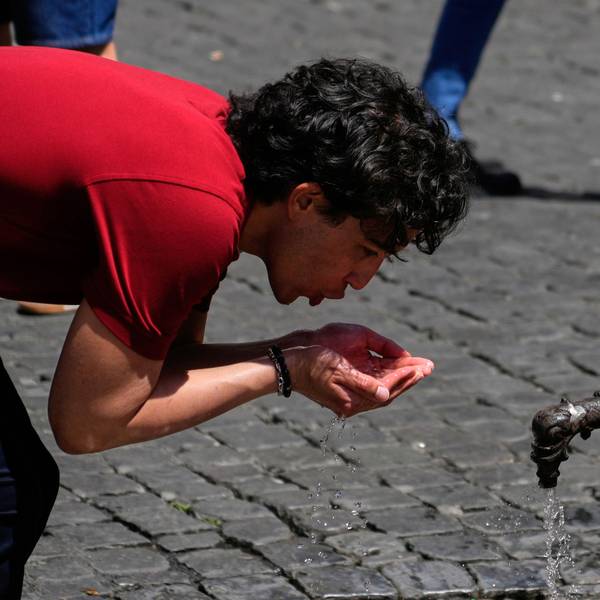 Italien, Rom: Ein Mann trinkt Wasser an einem Brunnen in der Innenstadt, während die Temperaturen auf mehr als 30 Grad Celsius steigen.