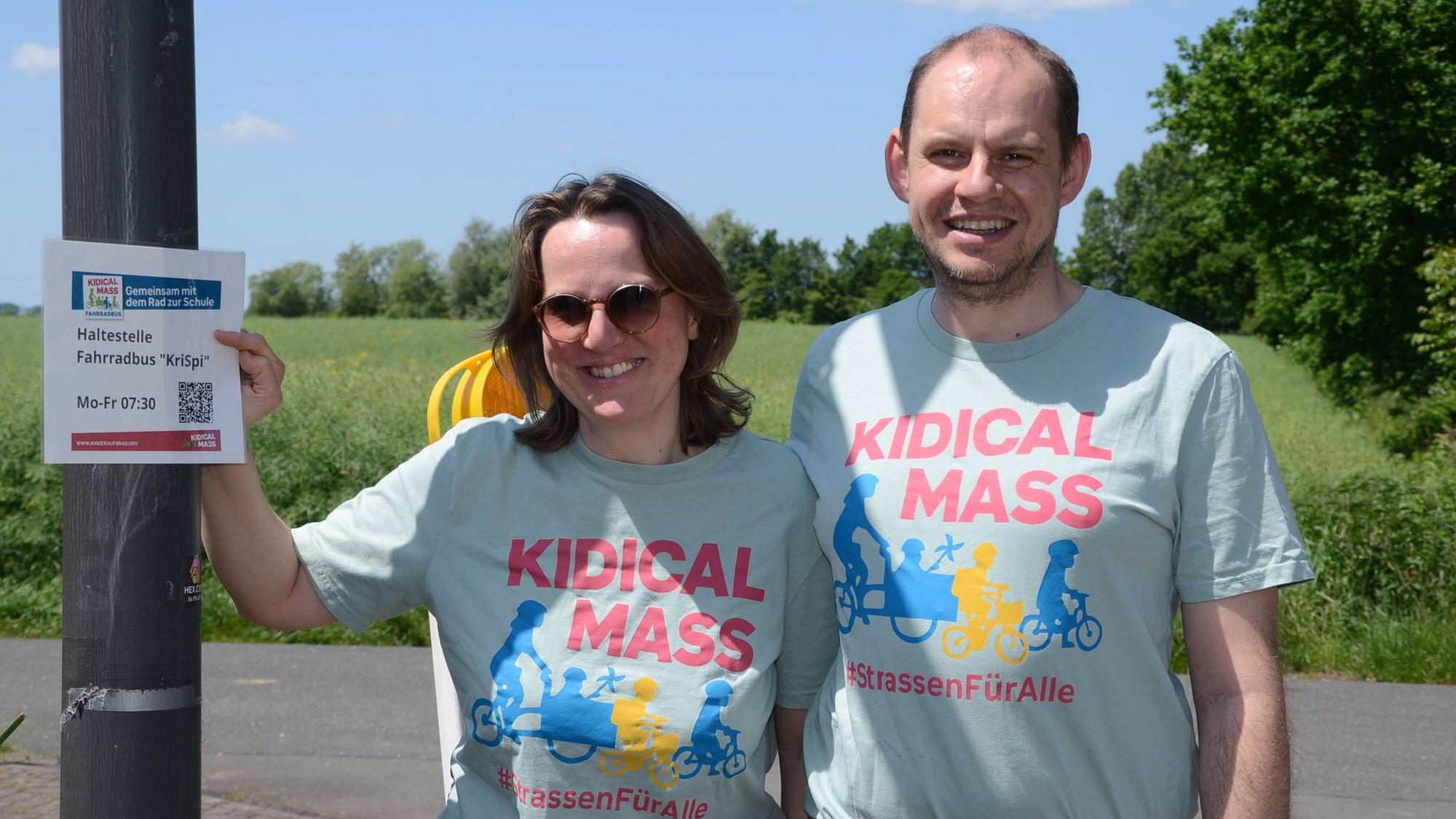 Ein Mann und eine Frau in hellblauen T-Shirts mit der Aufschrift Kidical Mass.