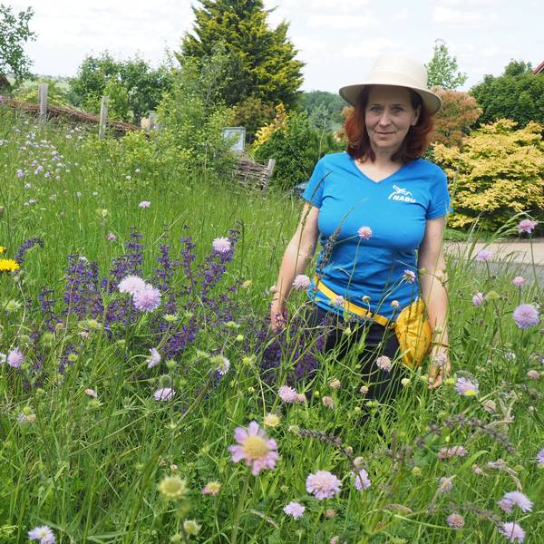 Anna Hofmeister trägt einen Sonnenhut und steht in einer blühenden Wiese.