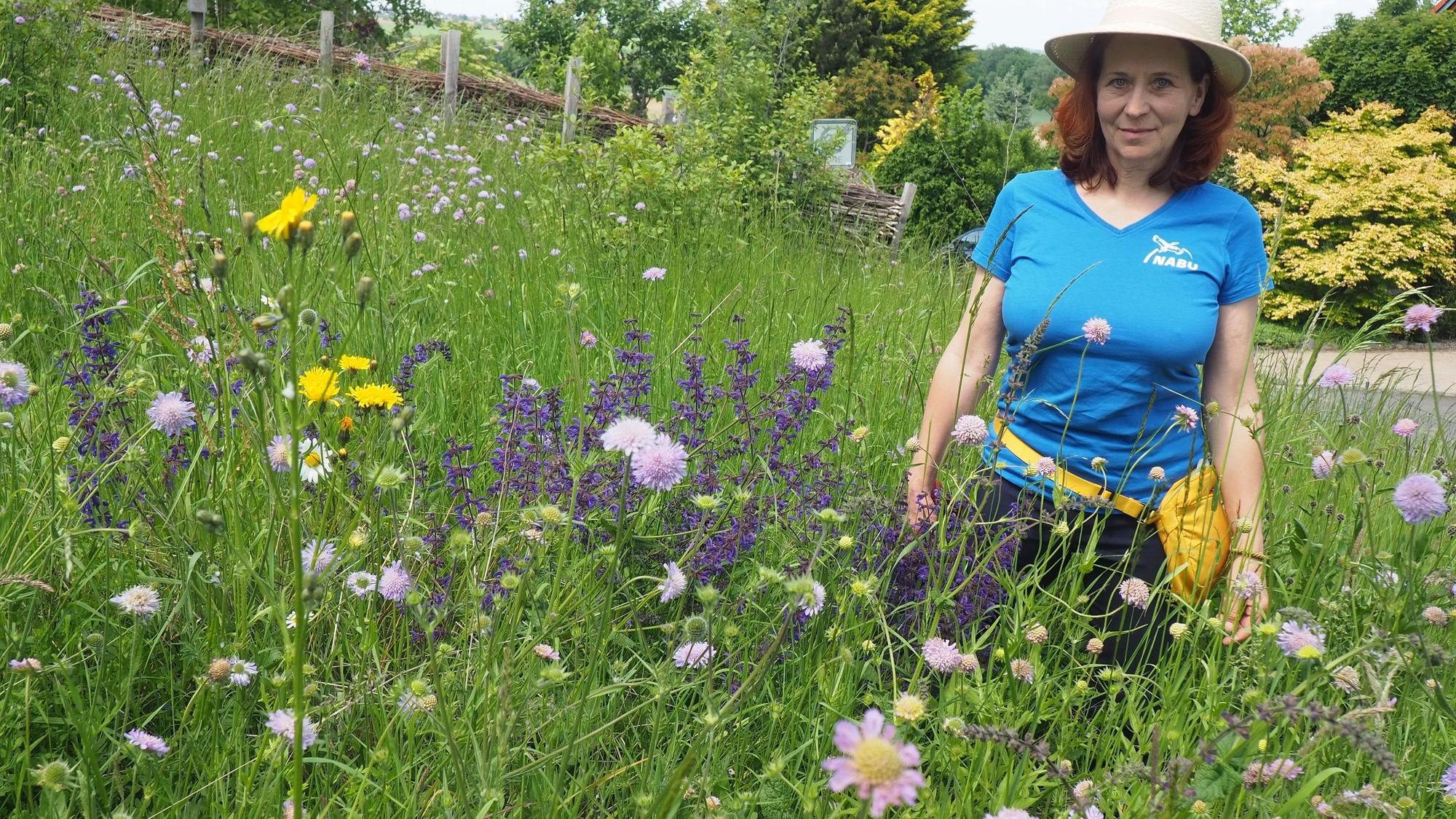 Anna Hofmeister trägt einen Sonnenhut und steht in einer blühenden Wiese.
