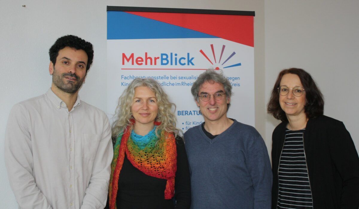 Das Team von Mehrblick steht vor einem Banner.