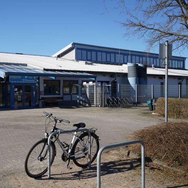Das Foto zeigt ein Schwimmbad von außen, davor ein Fahrrad.