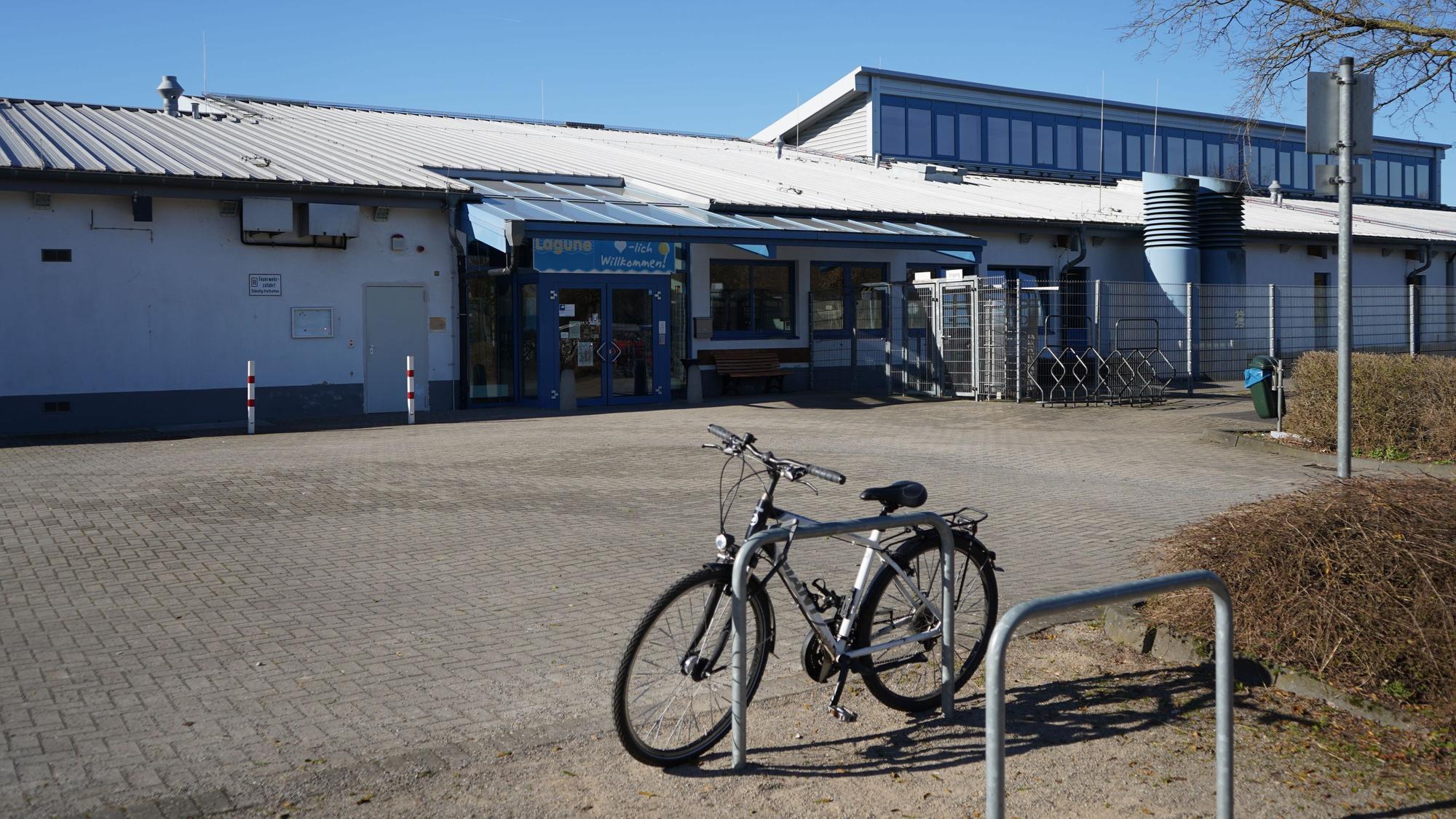 Das Foto zeigt ein Schwimmbad von außen, vorne steht ein Fahrrad.