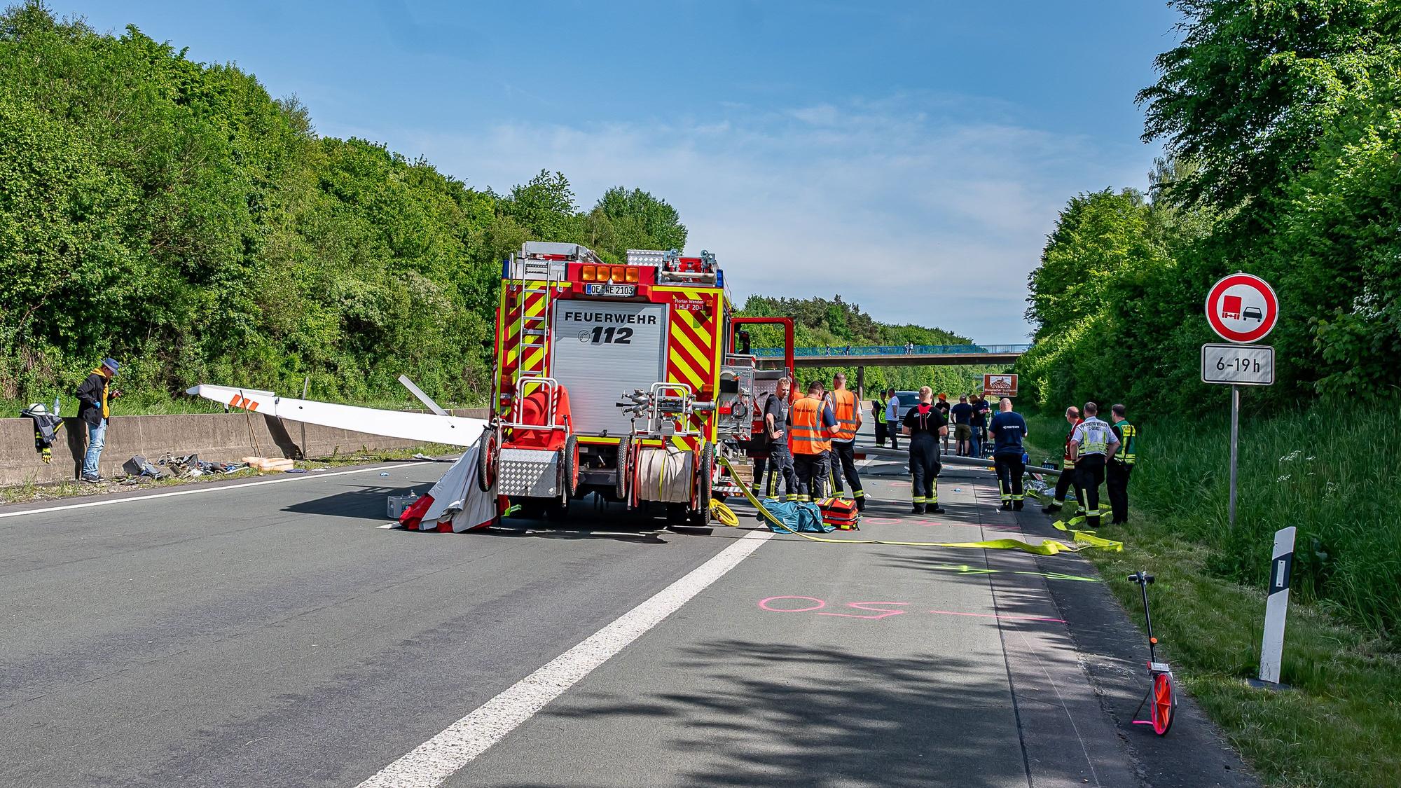 Ein Feuerwehrfahrzeug steht auf der Straße vor dem abgestürzten Segelflugzeug auf der A45 bei Wenden-Hünsborn.