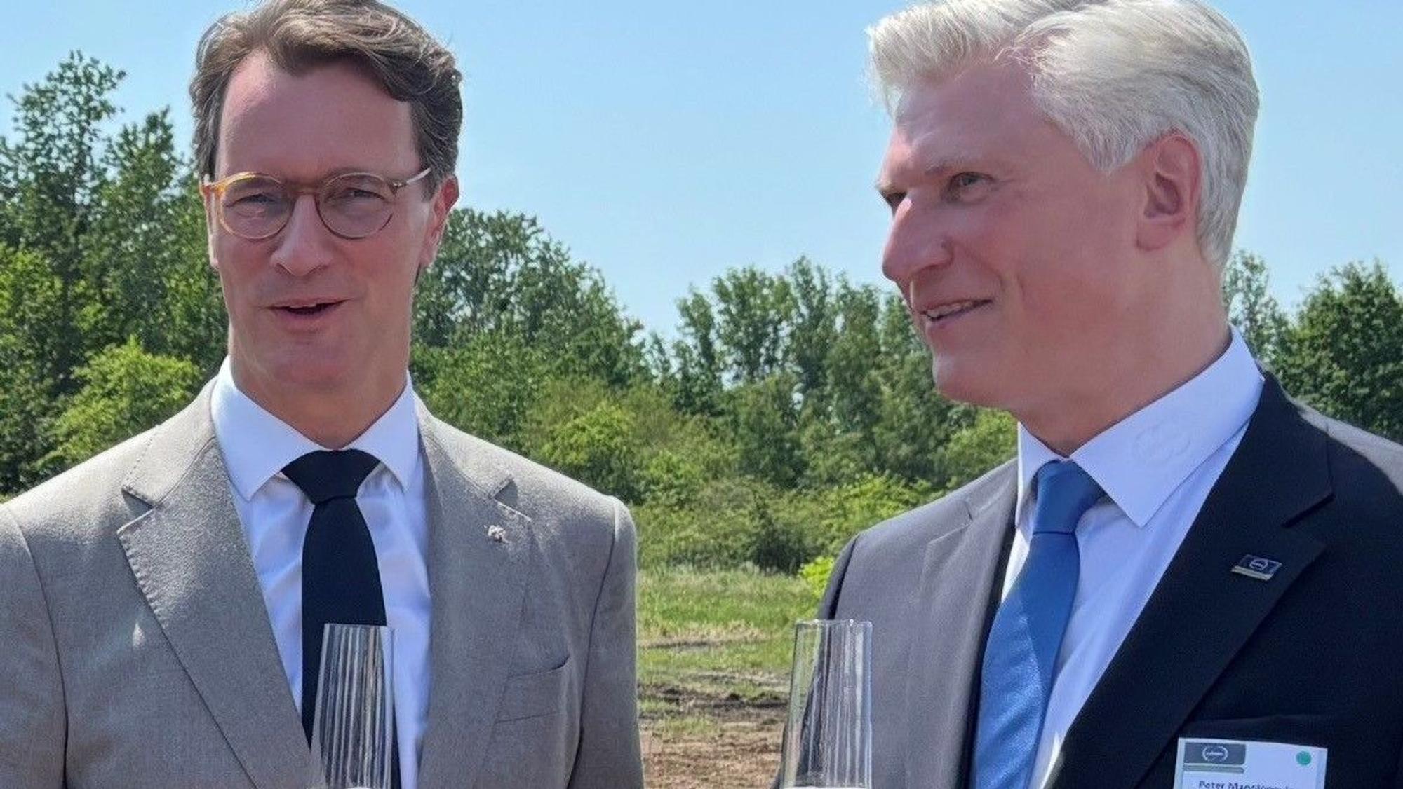 Auf dem Bild sind zwei Männer in Anzügen zu sehen.