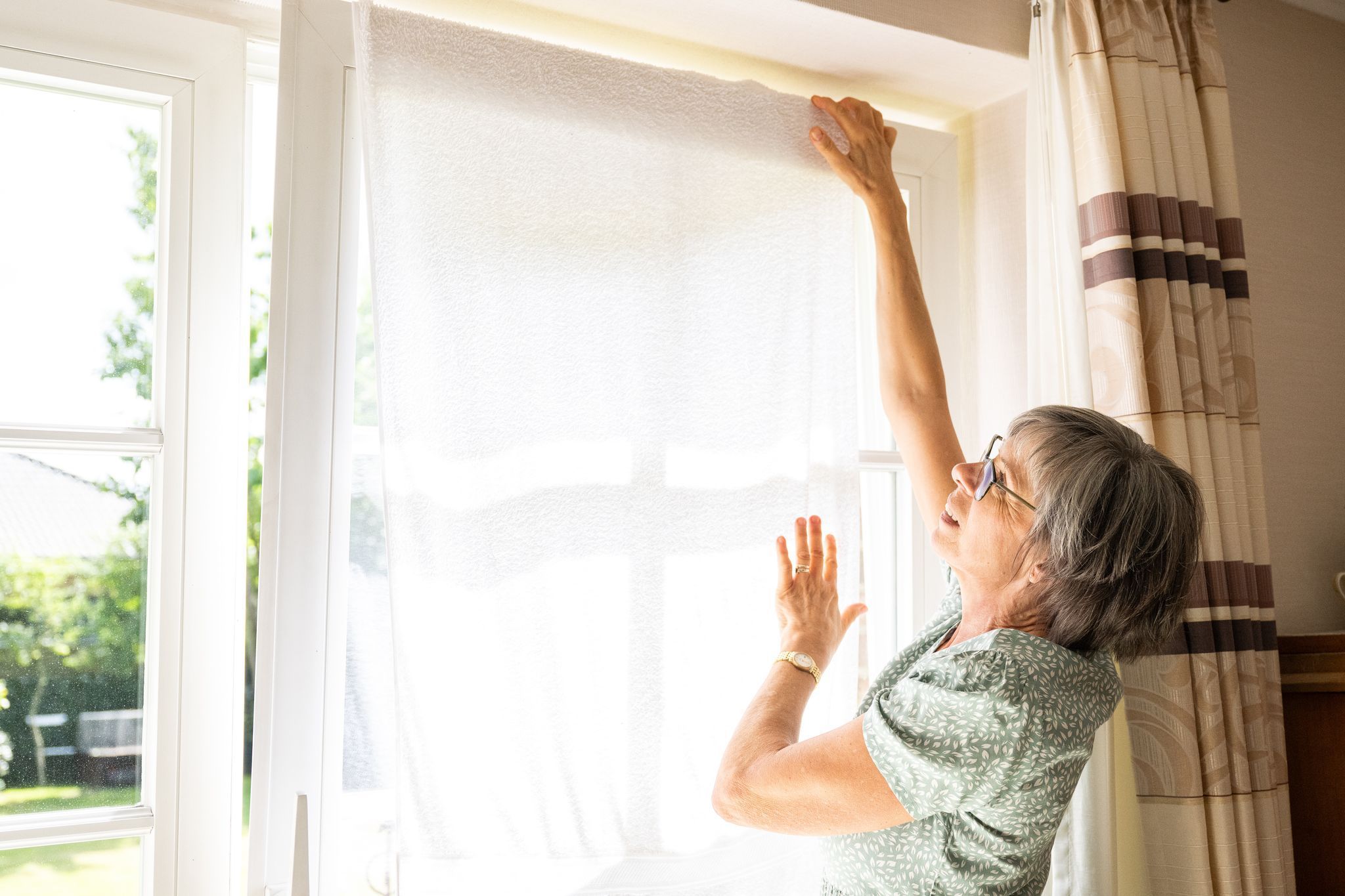 Eine Frau hängt ein nasses Handtuch vor ein Fenster