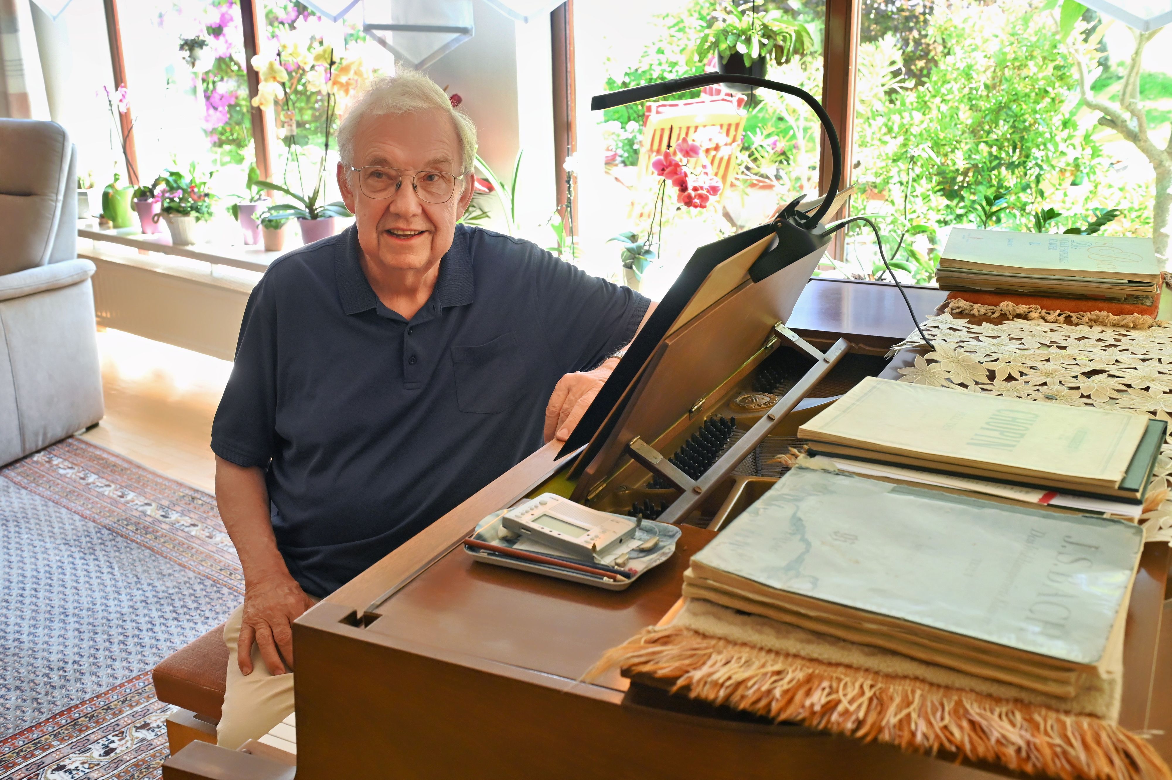 Paul F. Irmen sitzt in seinem Wohnzimmer in Marmagen an einem Klavier. Darauf liegen zahlreiche Notenbücher.