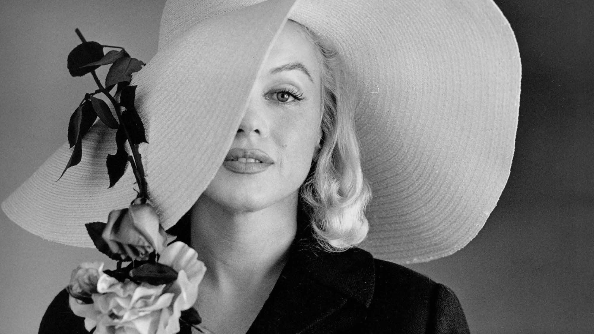 Marilyn Monroe trägt einen großen Hut.