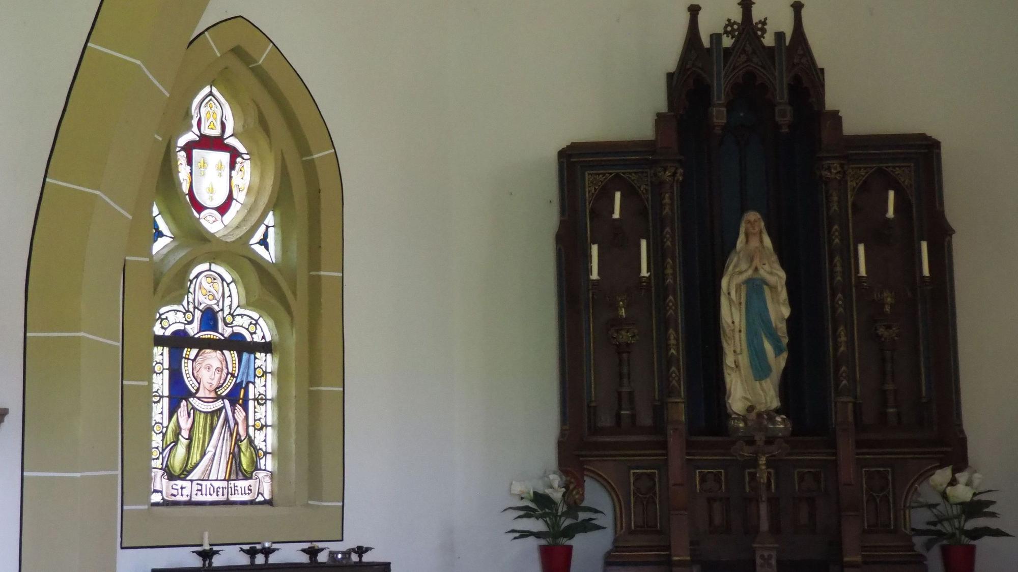 Das Bild zeigt das Innere der Kirche. Links befindet sich das Fenster mit der Darstellung des Alderikus, rechts daneben der Altar,