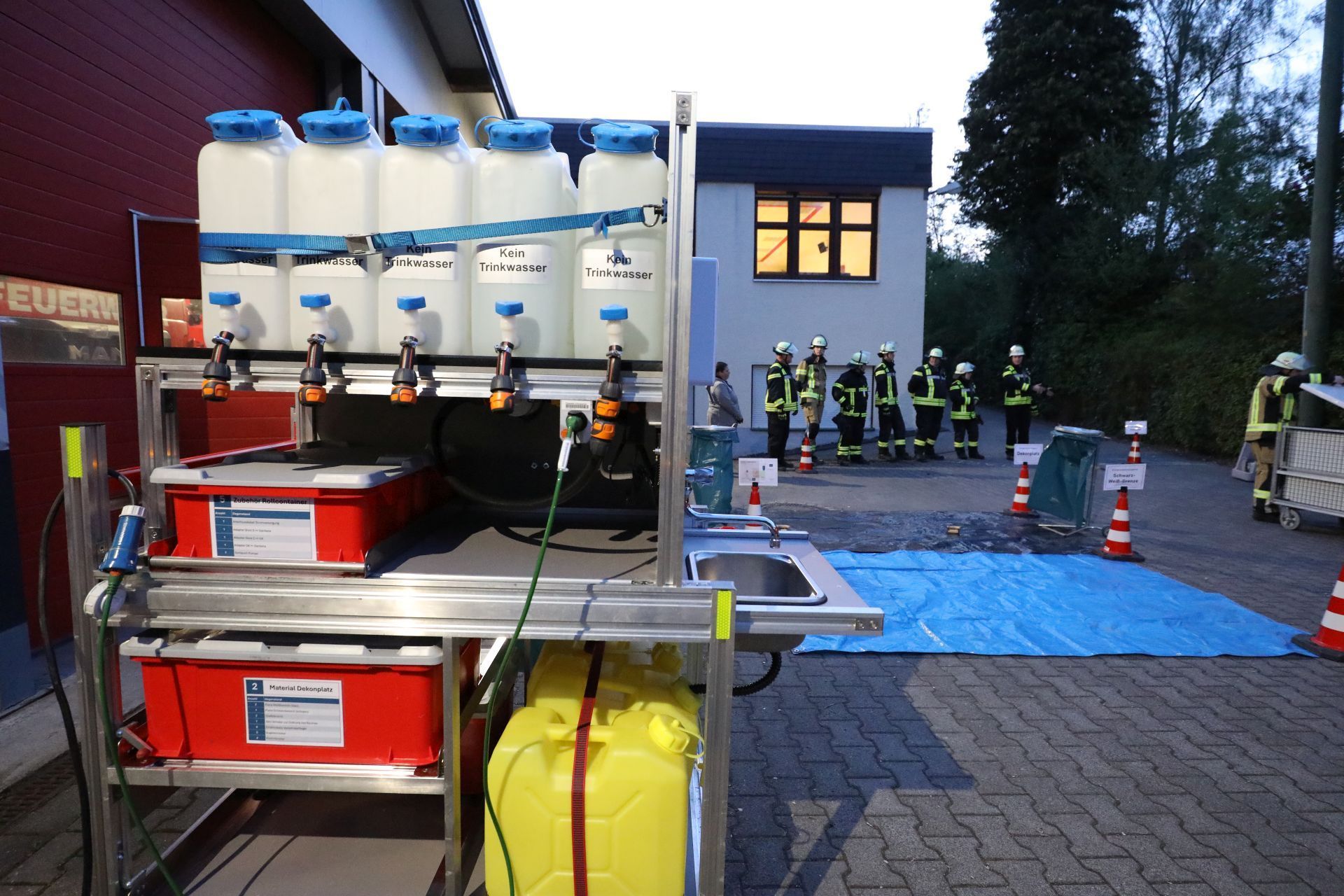 Ein Rollcontanier mit Wasserbehältern, am Rand ein kleines Waschbecken mit Wasserhahn.