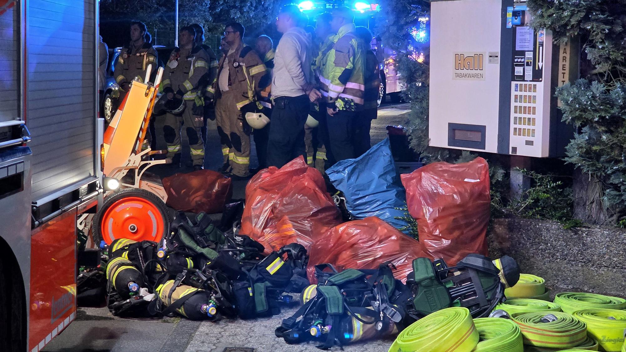 Säcke mit Einsatzkleidung liegen neben Pressluftatmer-Flaschen neben einem Feuerwehrfahrzeug.