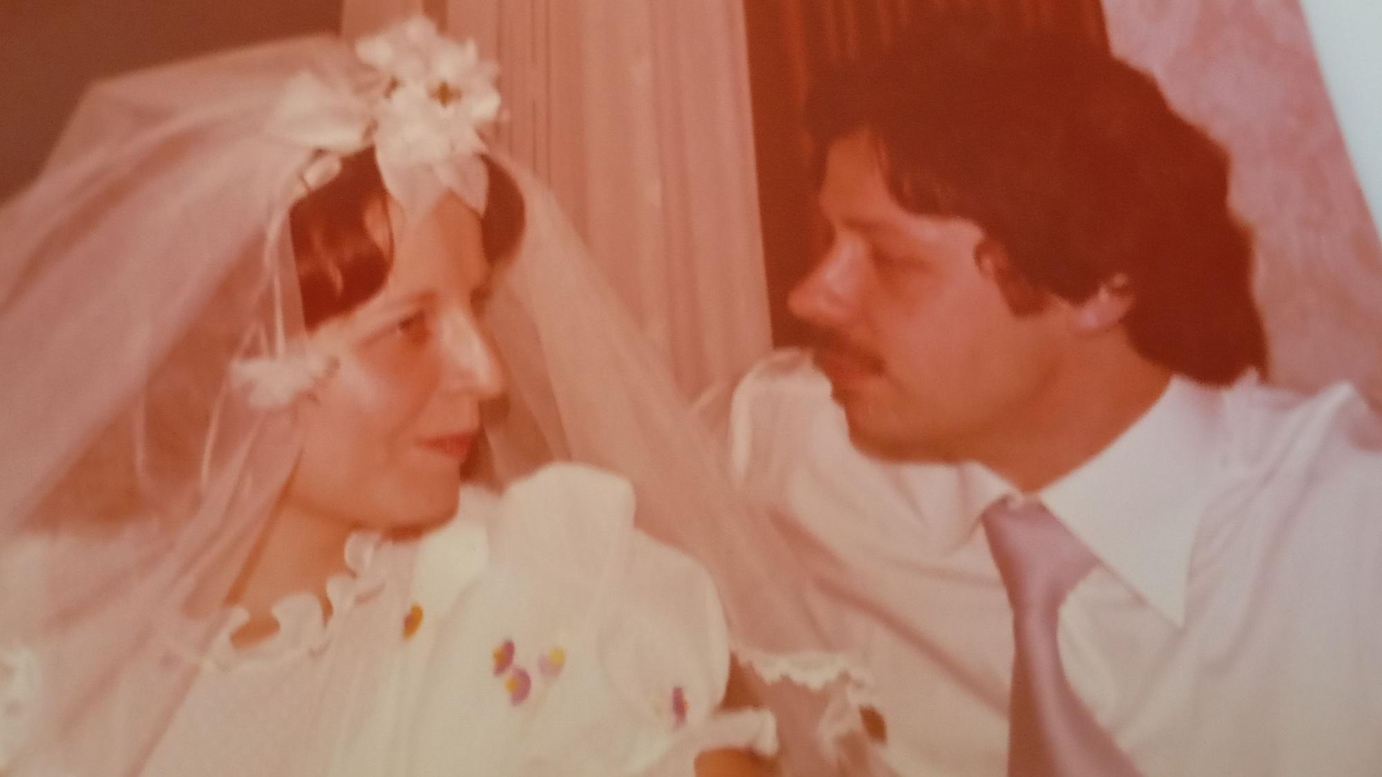 Zu sehen sind eine Braut und ihr Bräutigam an ihrem Hochzeitstag.