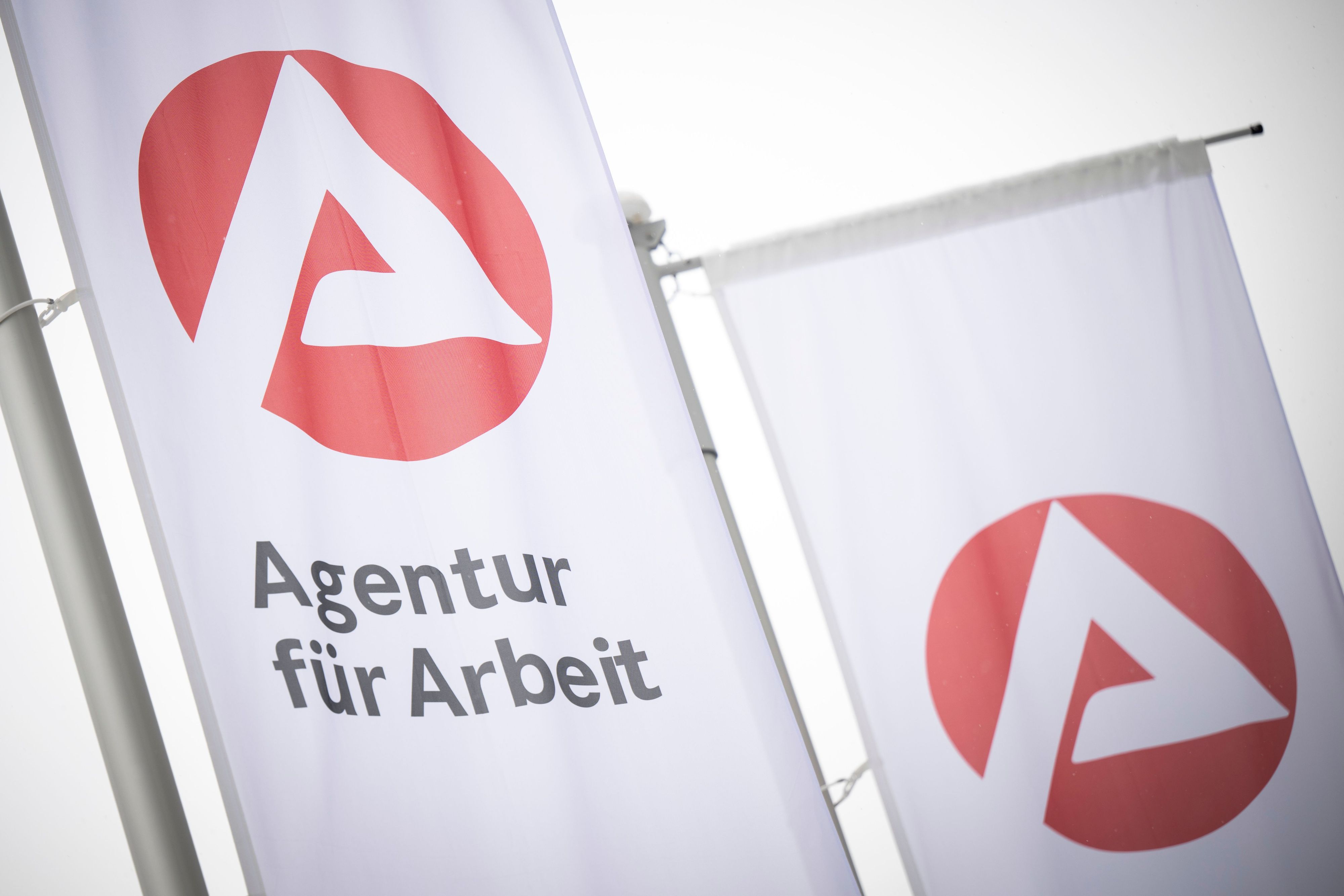 Fahnen mit dem Logo der Agentur für Arbeit wehen im Wind. (Symbolbild)
