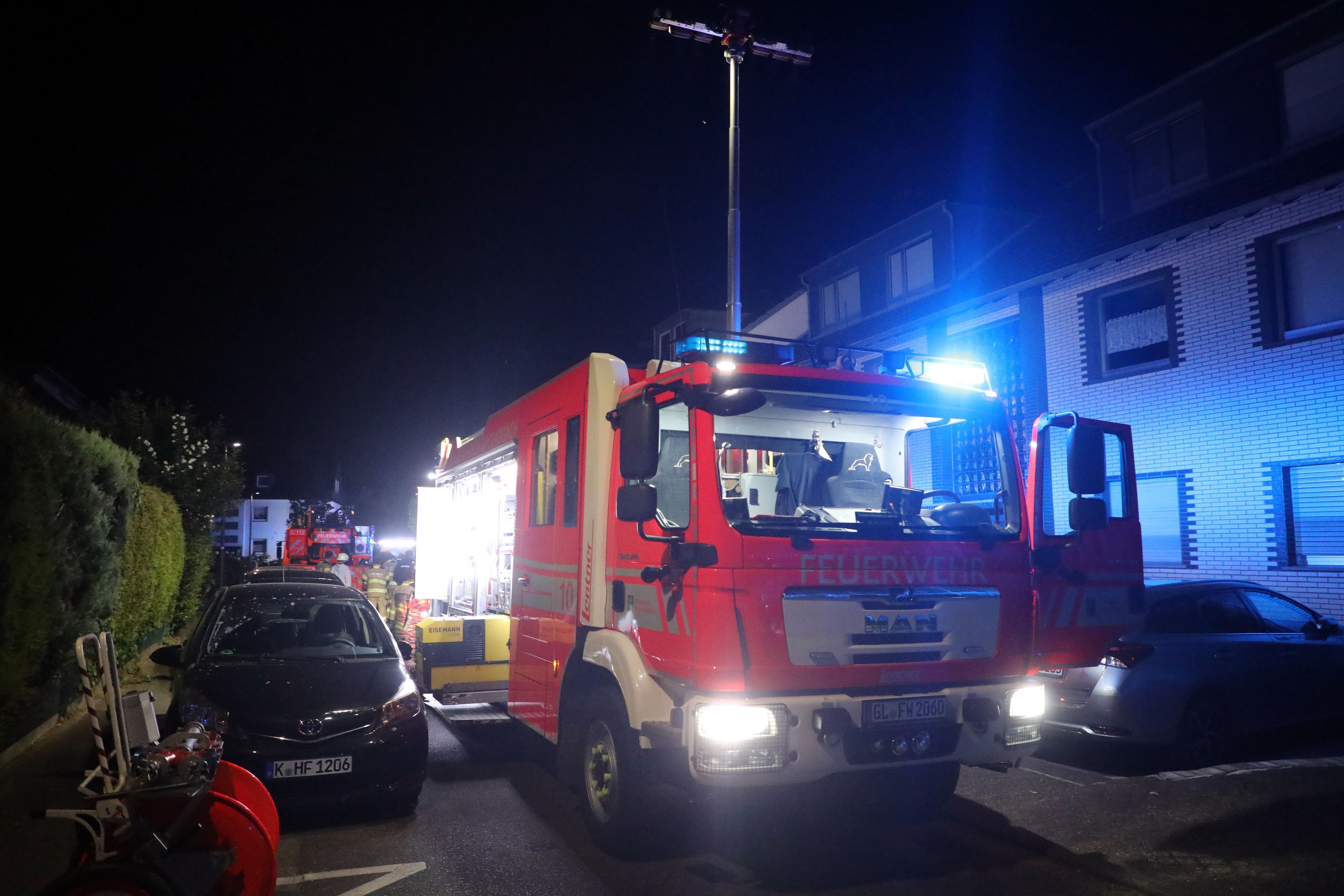 Ein Feuerwehrfahrzeug steht mit Blaulicht in einer Wohnstraße in Bergisch Gladbach-Lustheide.