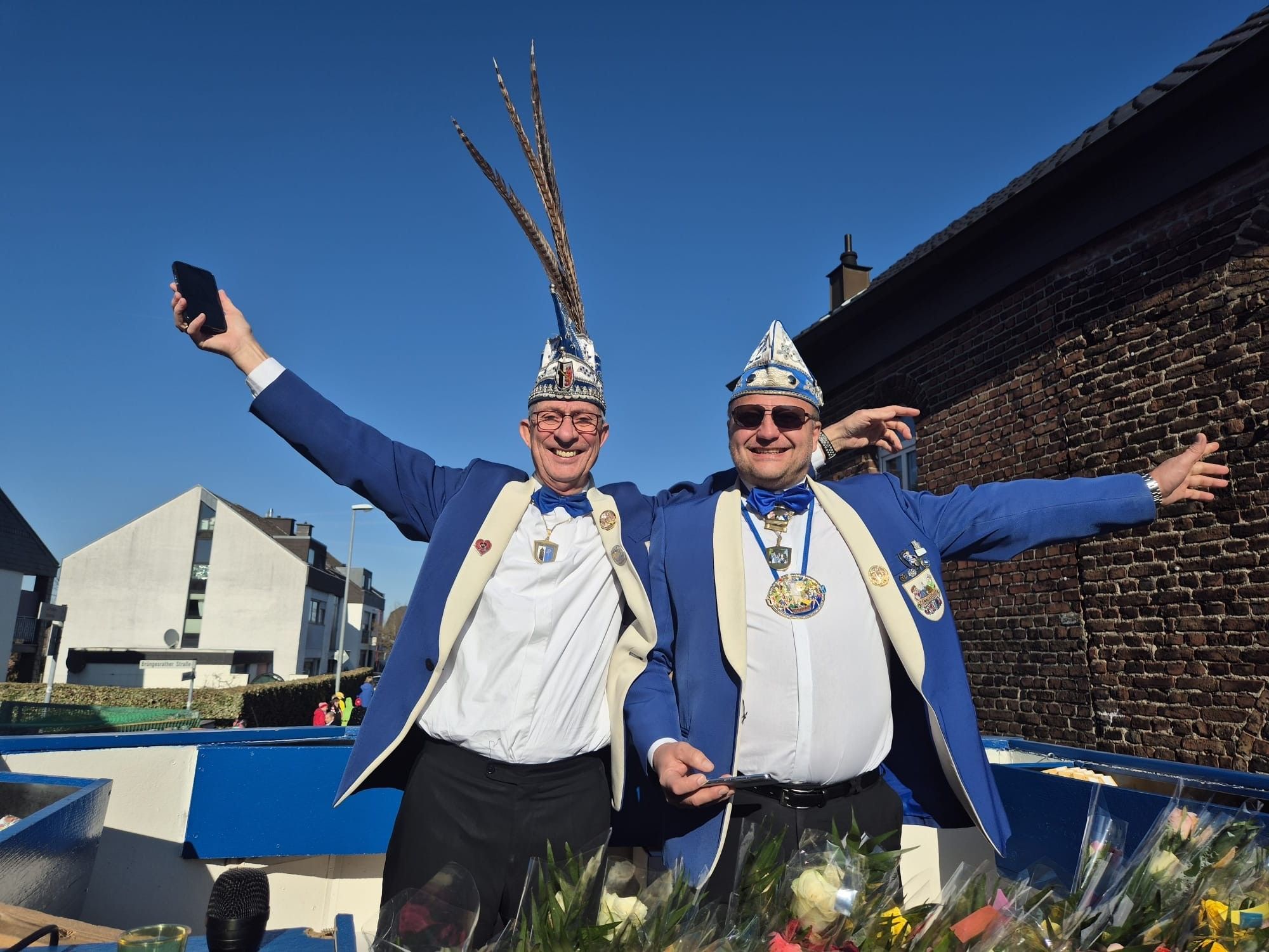 Zwei Männer strahlen beim Rosenmontagszug um die Wette.