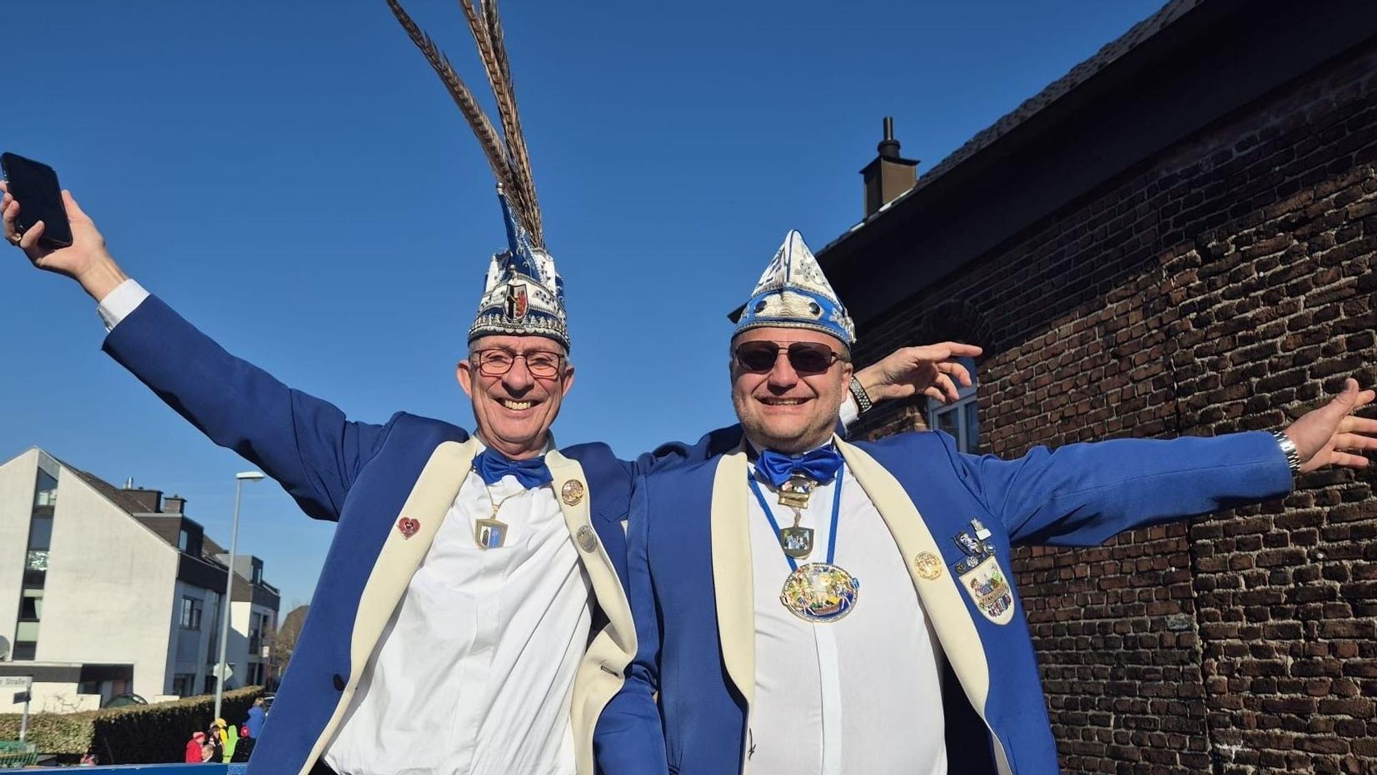 Zwei Männer strahlen beim Rosenmontagszug um die Wette.