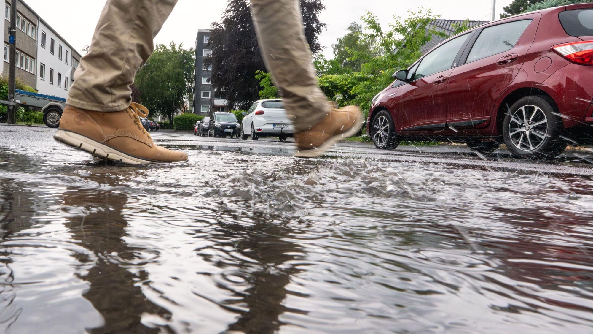 Ein Mann geht nach Regenschauern durch eine Pfütze. Der Sonntag begann in Nordrhein-Westfalen mit Regen und Gewittern.
