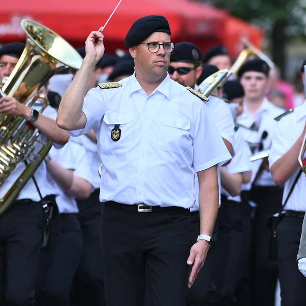 Ein Mann in Schützenuniform begrüßt einen Passanten.