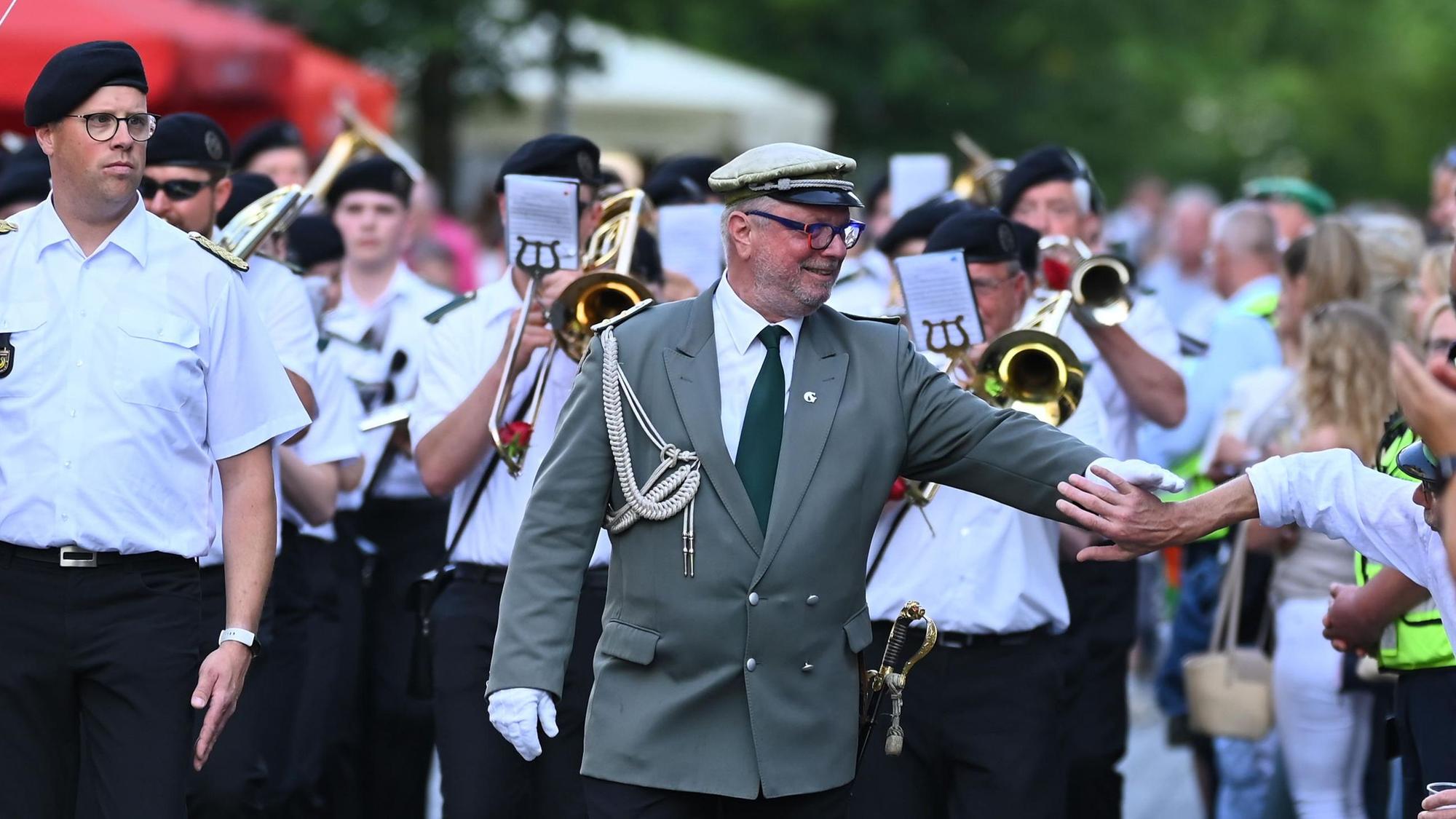 Ein Mann in Schützenuniform begrüßt einen Passanten.