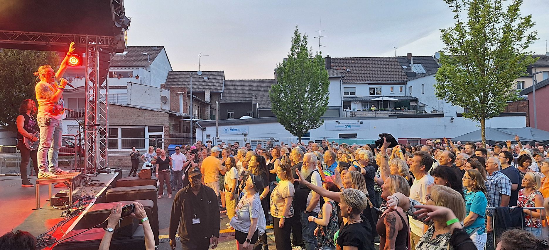 Das Foto zeigt die Band beim Auftritt und feiernde Fans vor der Bühne.