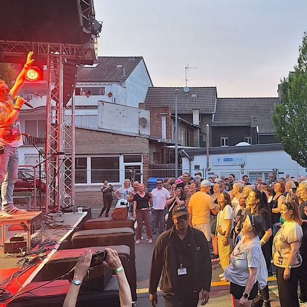 Das Foto zeigt die Band beim Auftritt und feiernde Fans vor der Bühne.