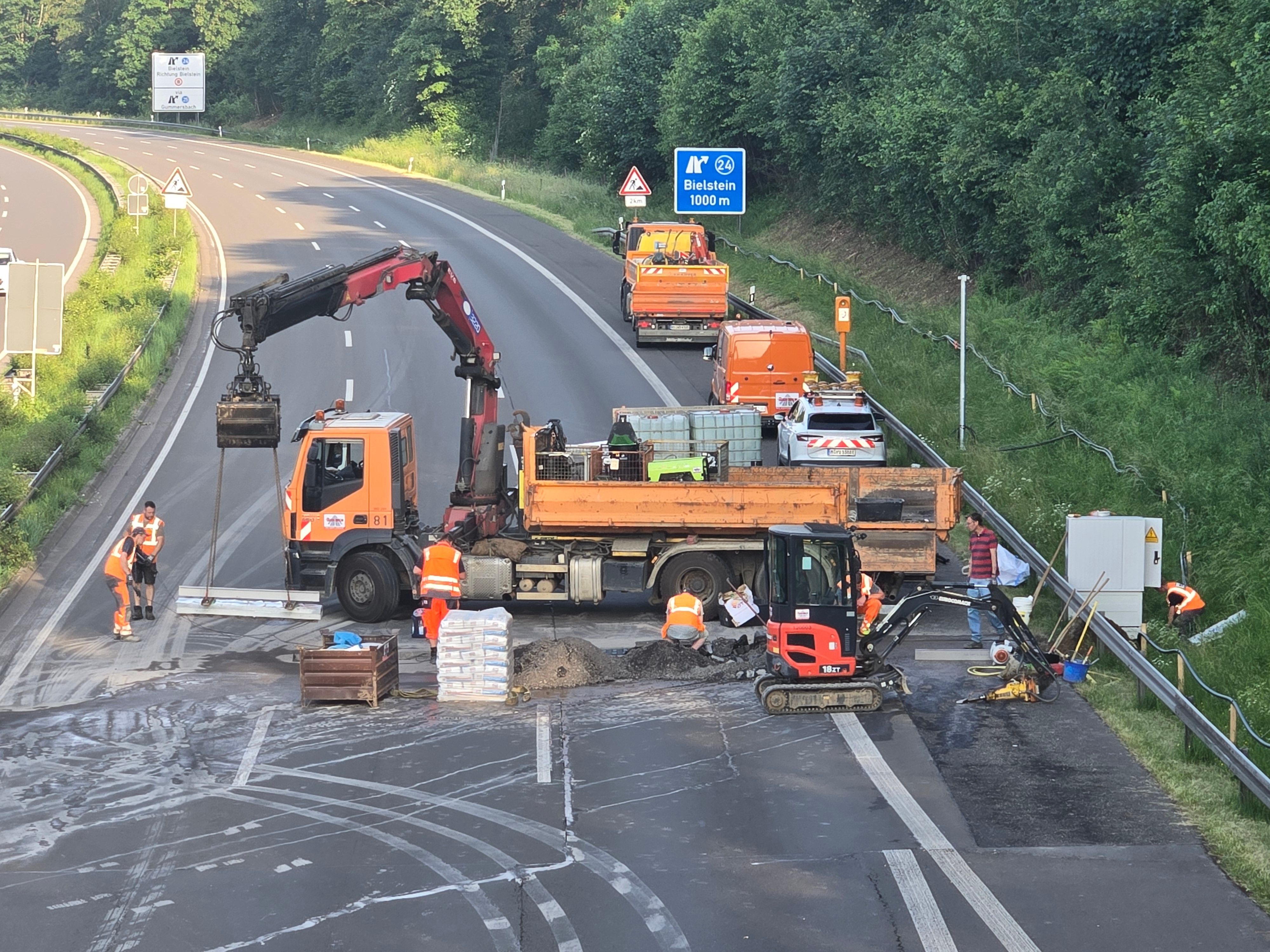 Ein großer Lkw quer auf der Fahrbahn, davor Bauarbeiter.