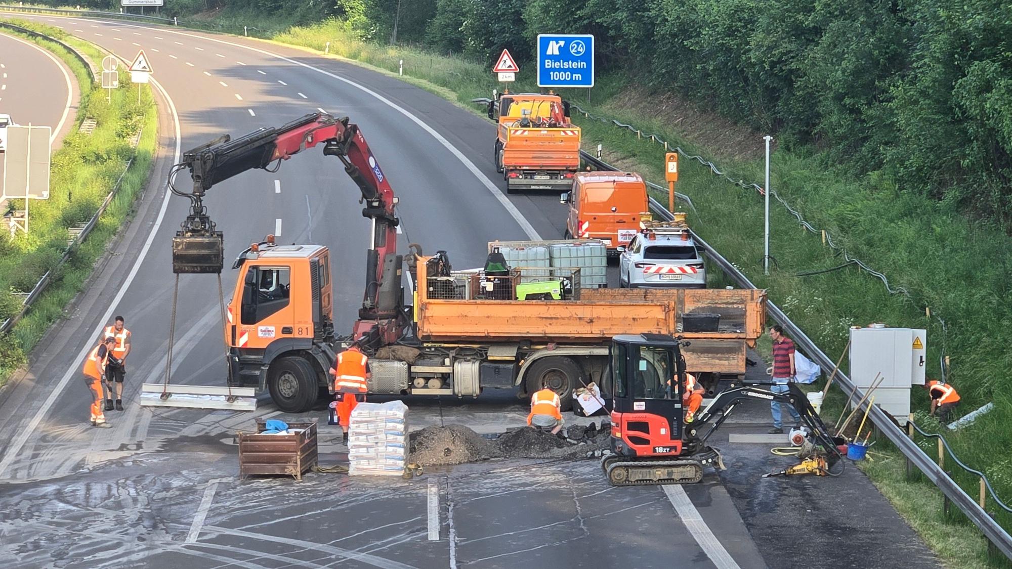 Ein großer Lkw quer auf der Fahrbahn, davor Bauarbeiter.