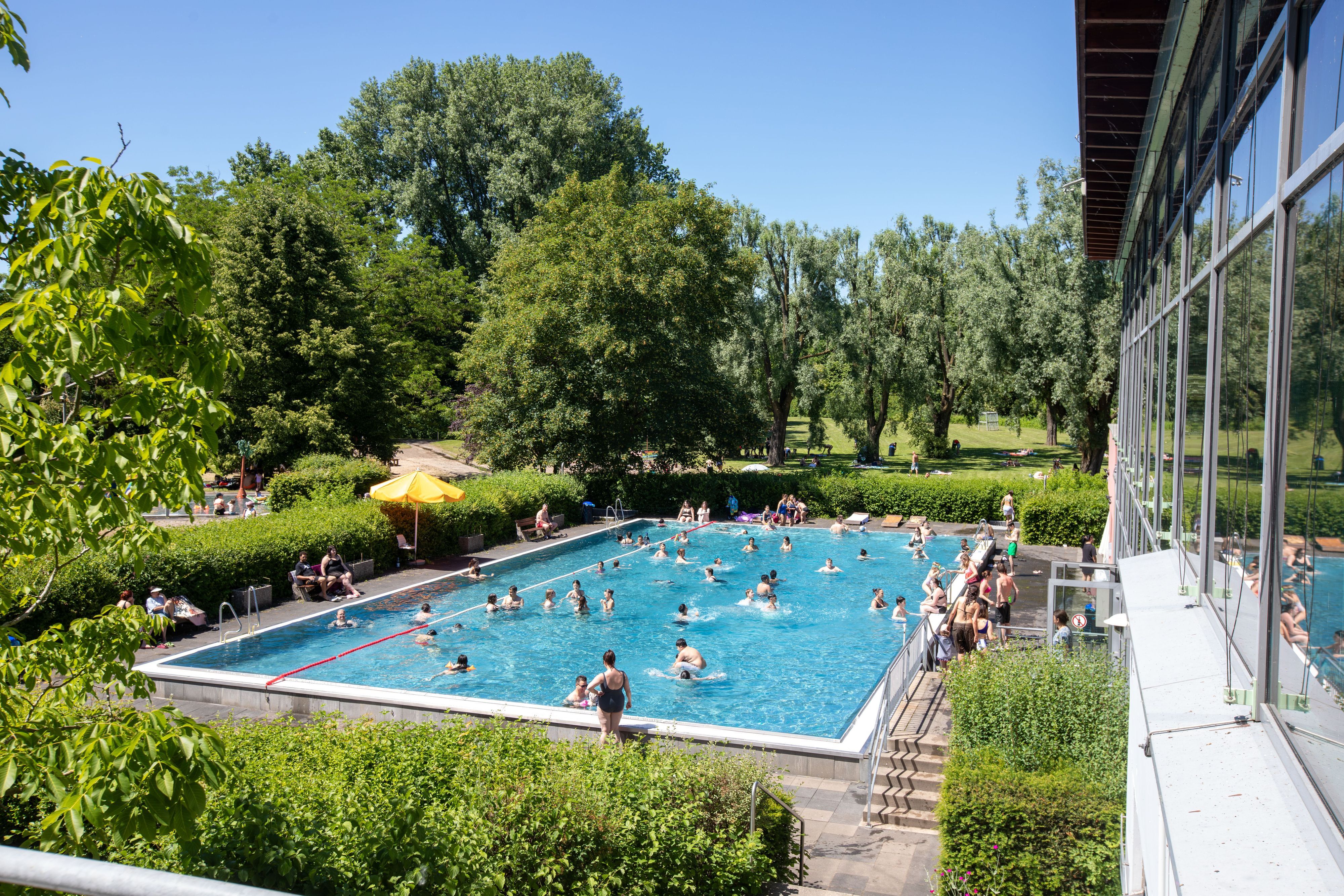 Zu sehen ist der riesige Außenbereich des Zündorfbads, mit Spielmöglichkeiten für Kinder und ein Schwimmerbecken.