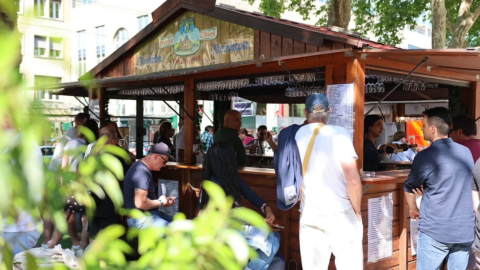 Leute stehen um einen Weinstand auf dem Kölner Neumarkt herum.