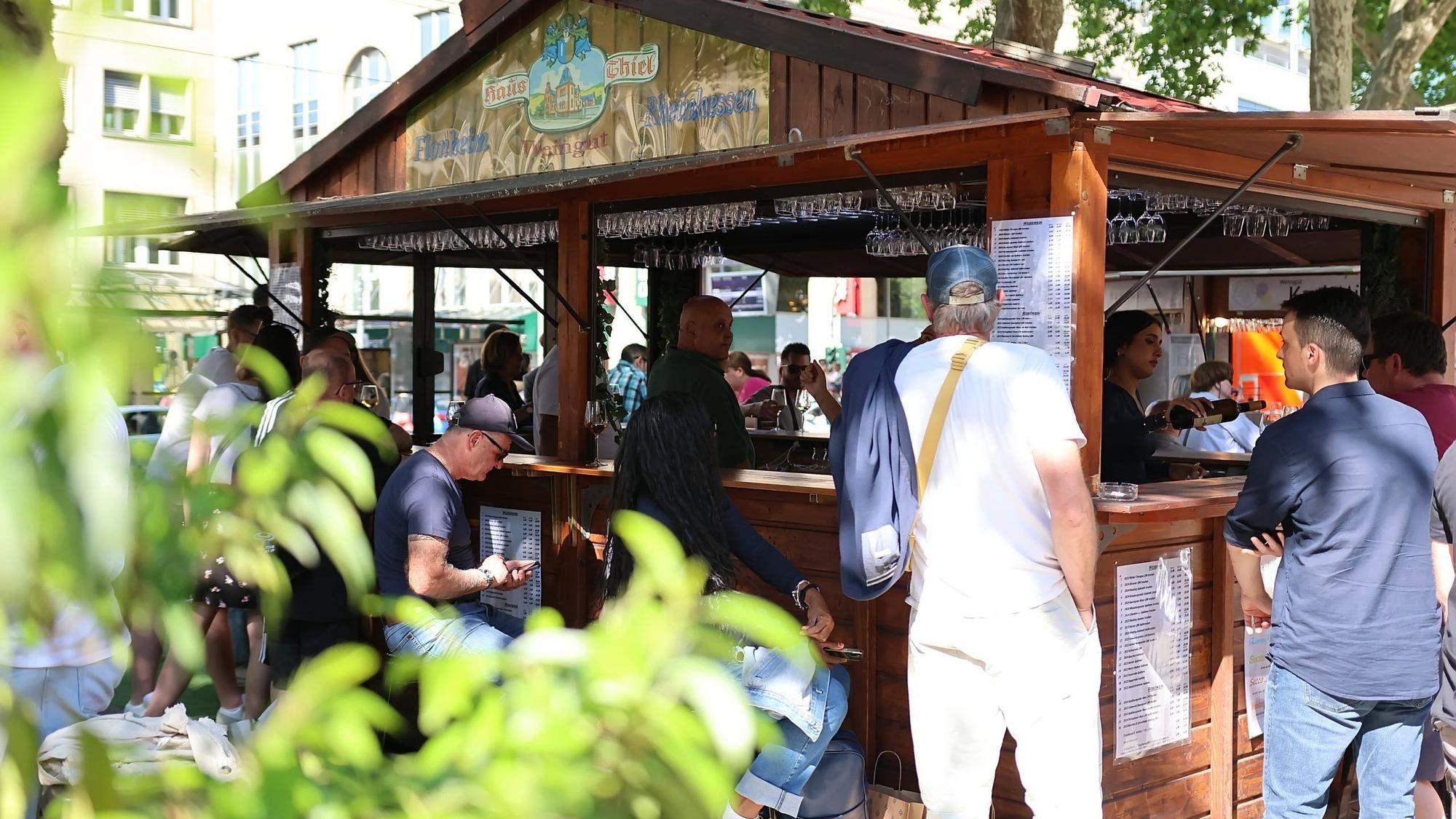 Leute stehen um einen Weinstand auf dem Kölner Neumarkt herum.