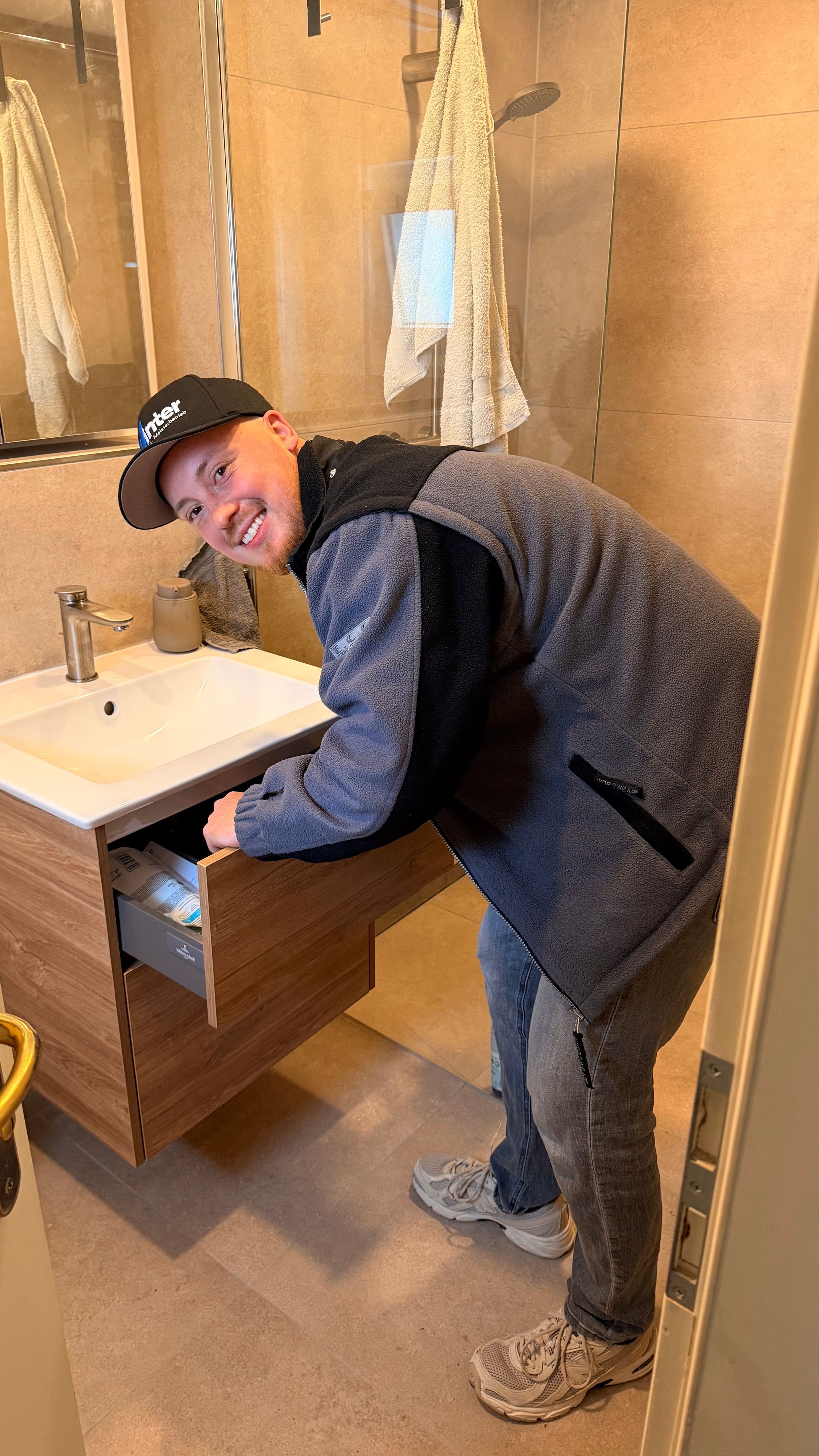 Ein junger Mann schaut in die Kamera, er beugt sich über ein Waschbecken.