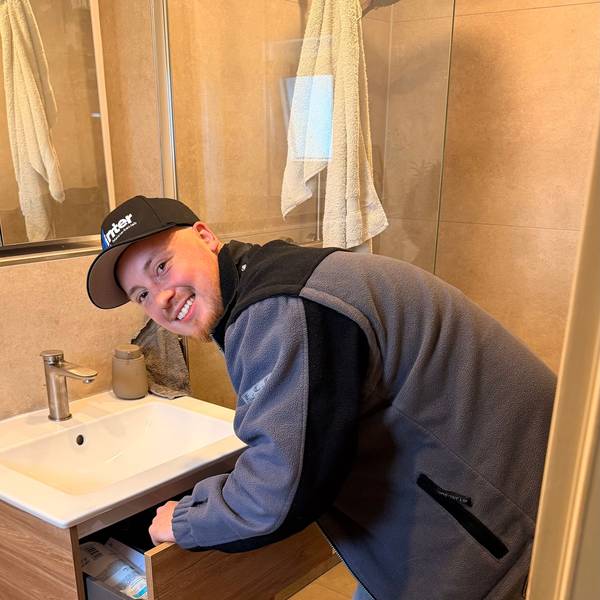 Ein junger Mann schaut in die Kamera, er beugt sich über ein Waschbecken.