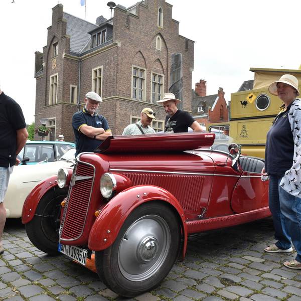 Menschen stehen um einen roten Adler Trumpf Junior Roadster von 1935 herum.