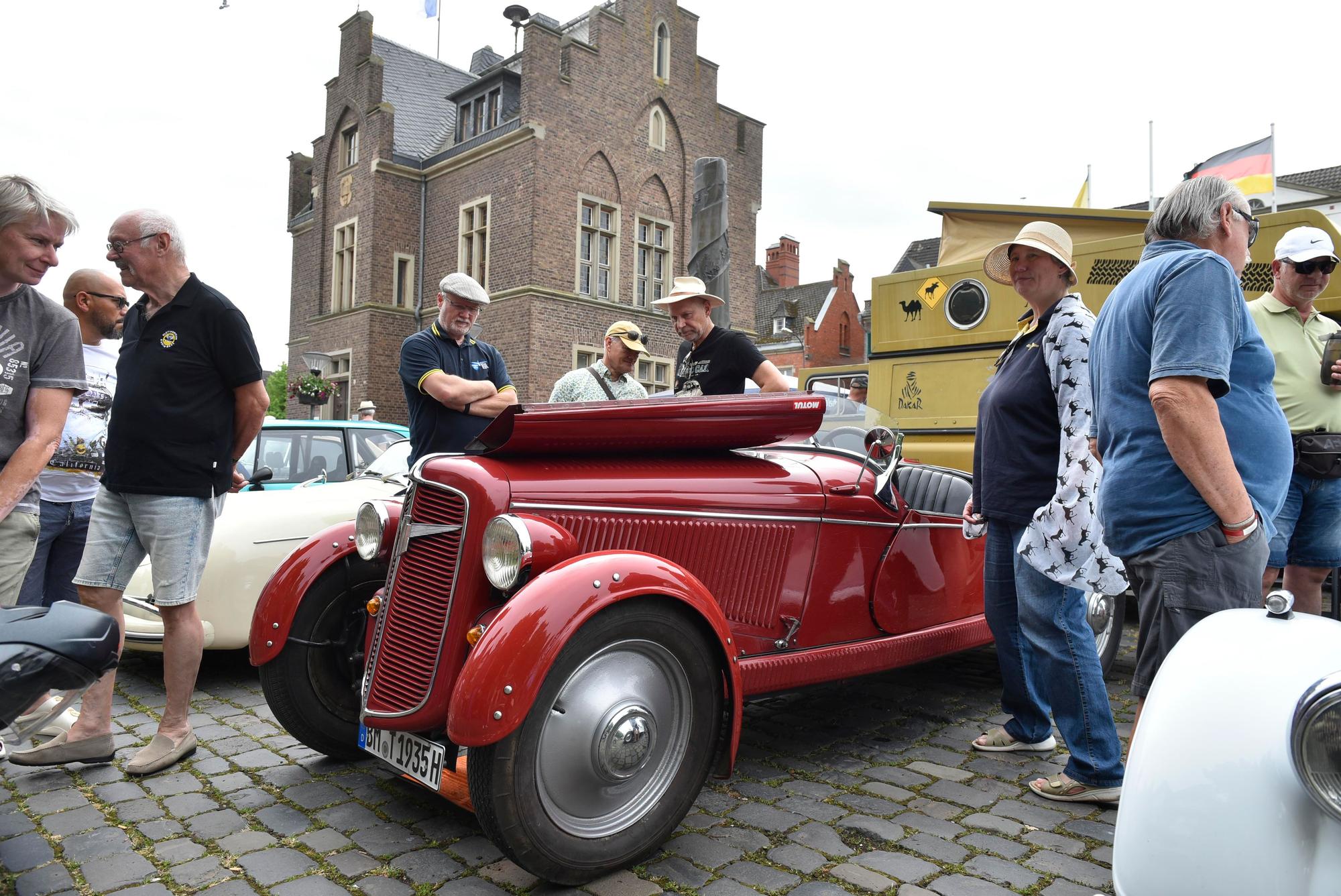 Menschen stehen um einen roten Adler Trumpf Junior Roadster von 1935 herum.
