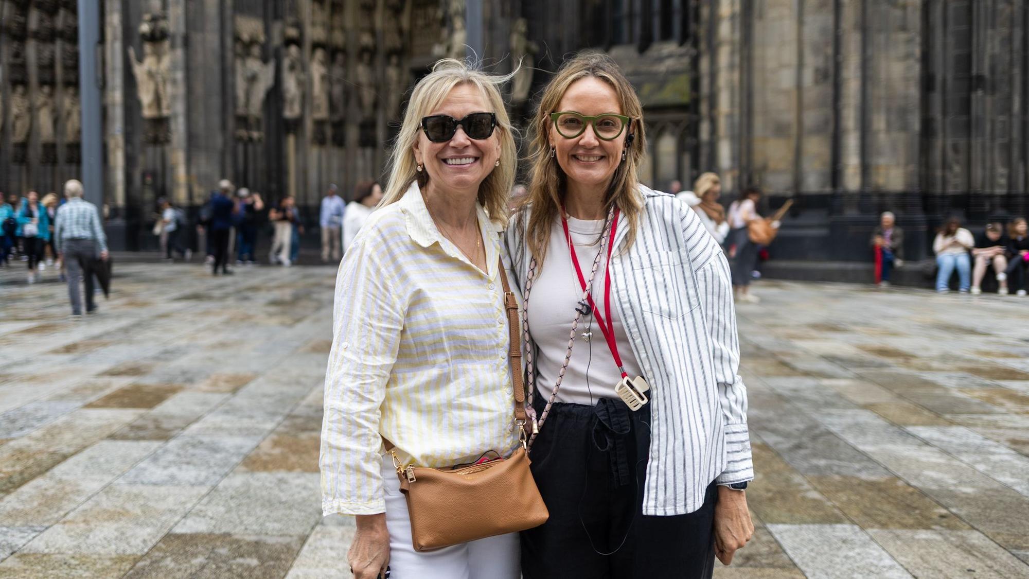 Zwei Frauen in gestreiften Hemden vor dem Kölner Dom.