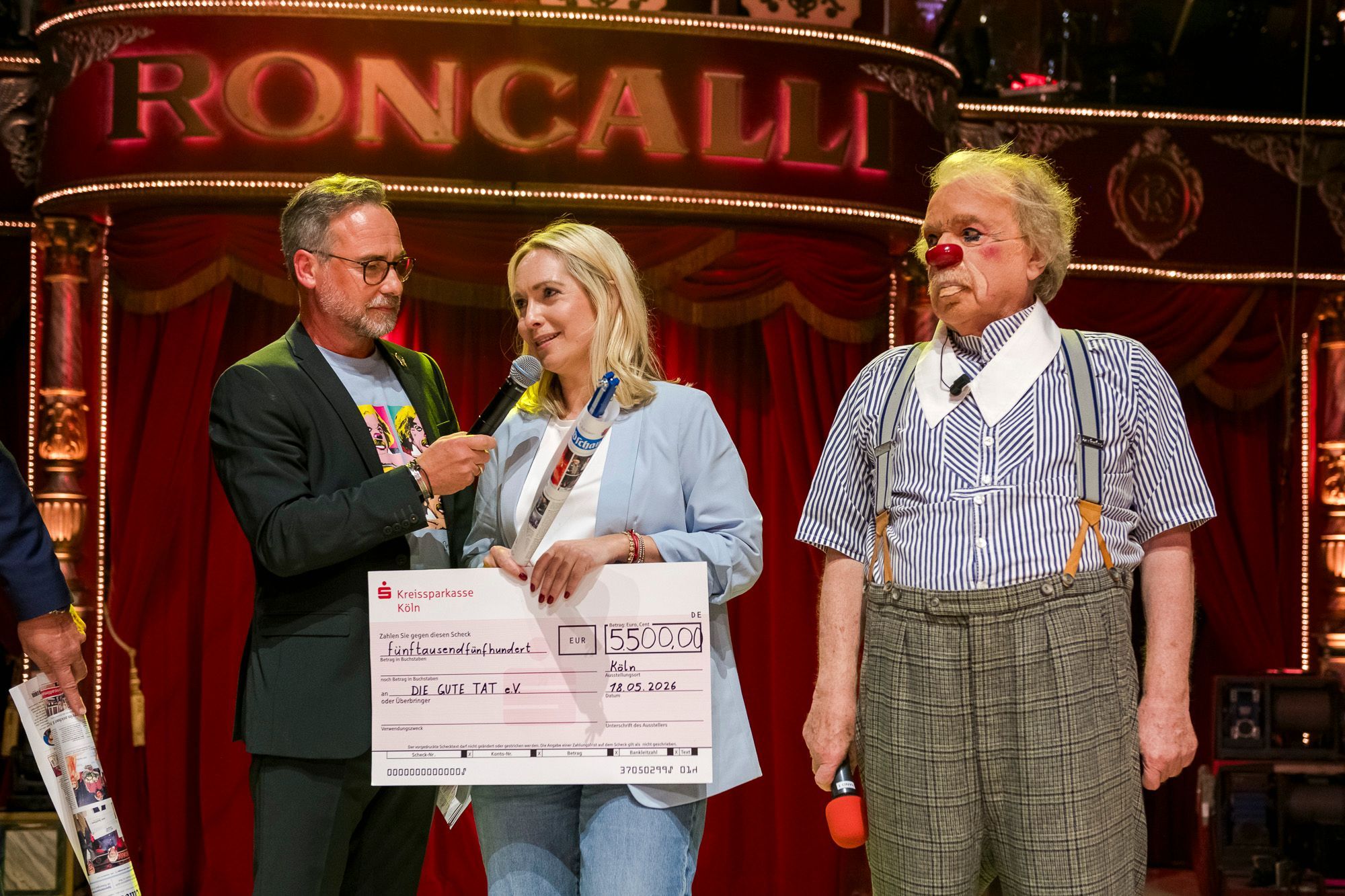 Ein Scheck für die Rundschau-Altenhilfe: Bernhard Paul (rechts) spendet den Gewinn aus der Jubiläumsgala. Julia Heinen erklärt Moderator Matthias Opdenhövel, was DIE GUTE TAT e.V. mit dem Geld macht.